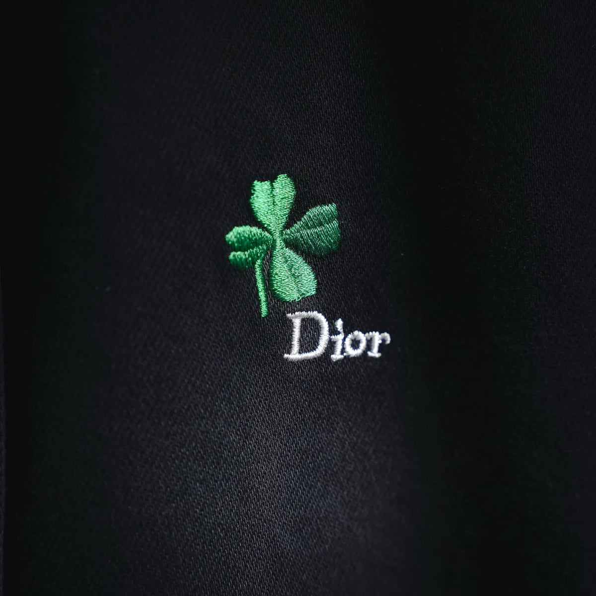 Green clover embroidery with Dior text on black shirt fabric