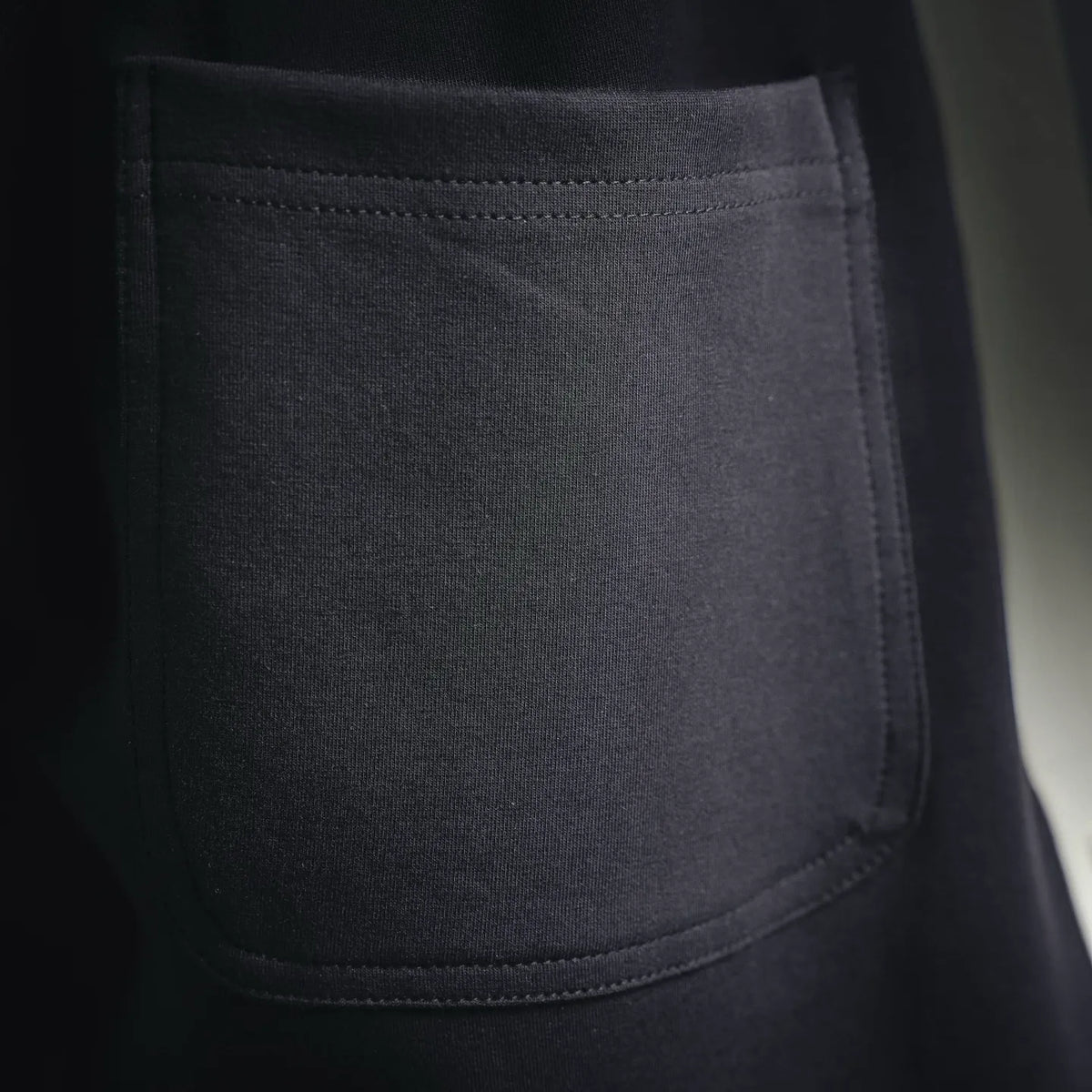 Black shorts with large front patch pocket and stitched seams on knit fabric