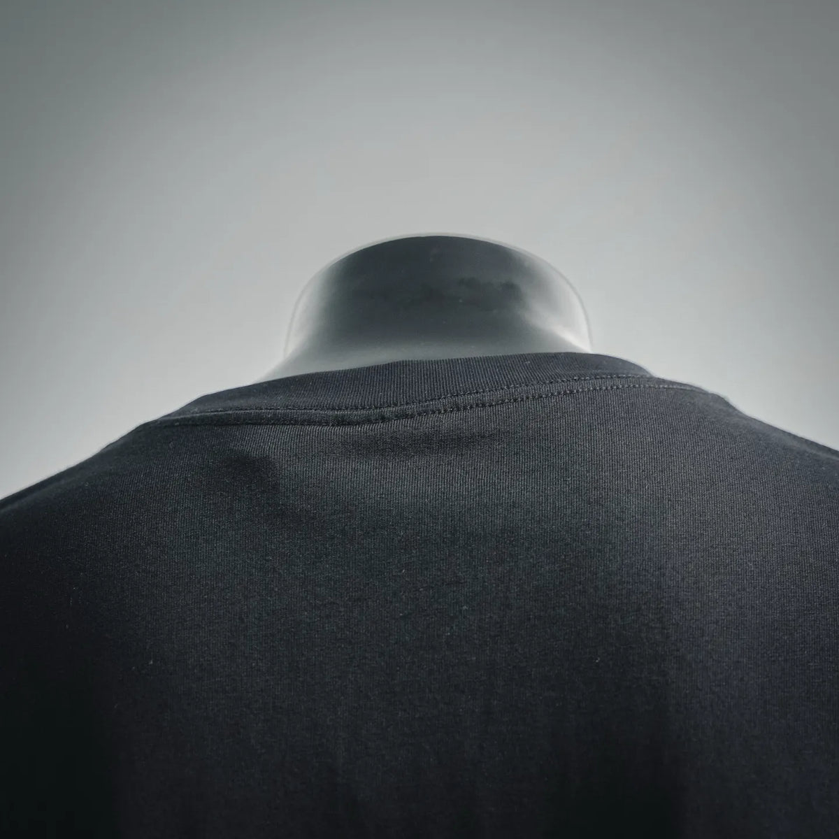 Black crewneck T-shirt back view, neckline seam visible at shoulder
