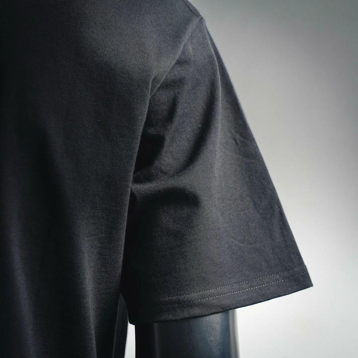 Black T-shirt side view with short sleeve seam and smooth fabric texture