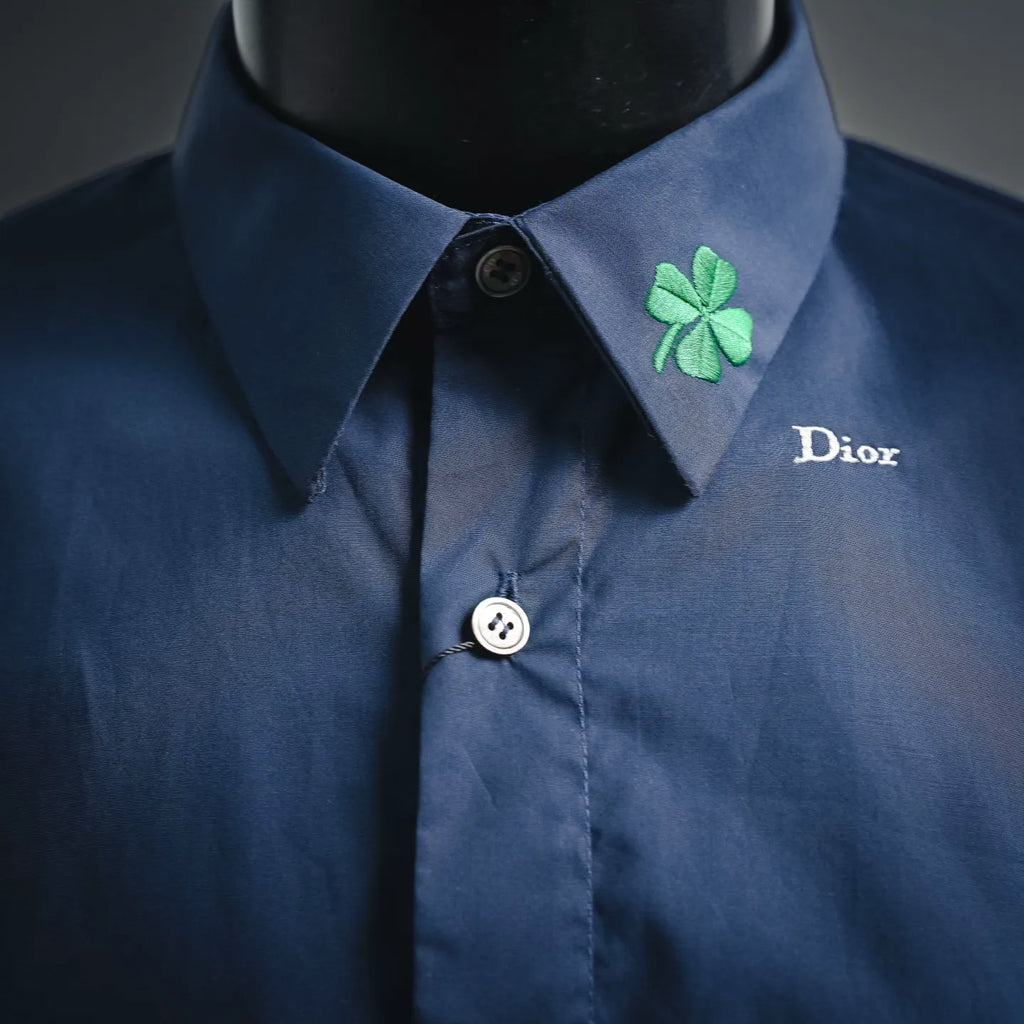 Dior short-sleeve shirt neckline close-up: dark blue collar, green clover patch, button
