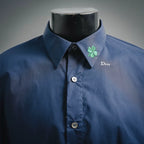 Dior dark blue short-sleeve button-up shirt on mannequin with green clover pin and collar logo