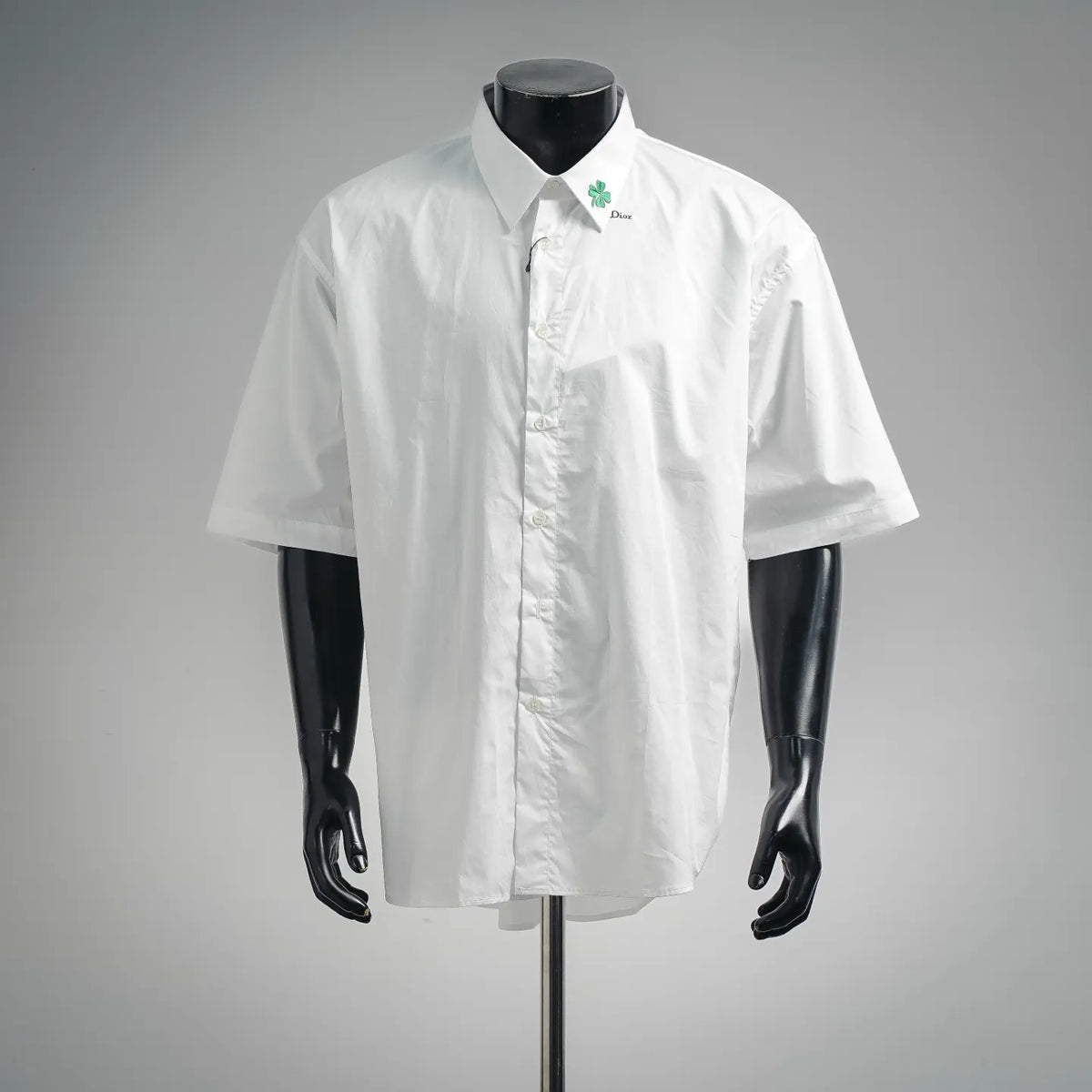 White short-sleeve button-up shirt on mannequin, front button placket, Dior logo