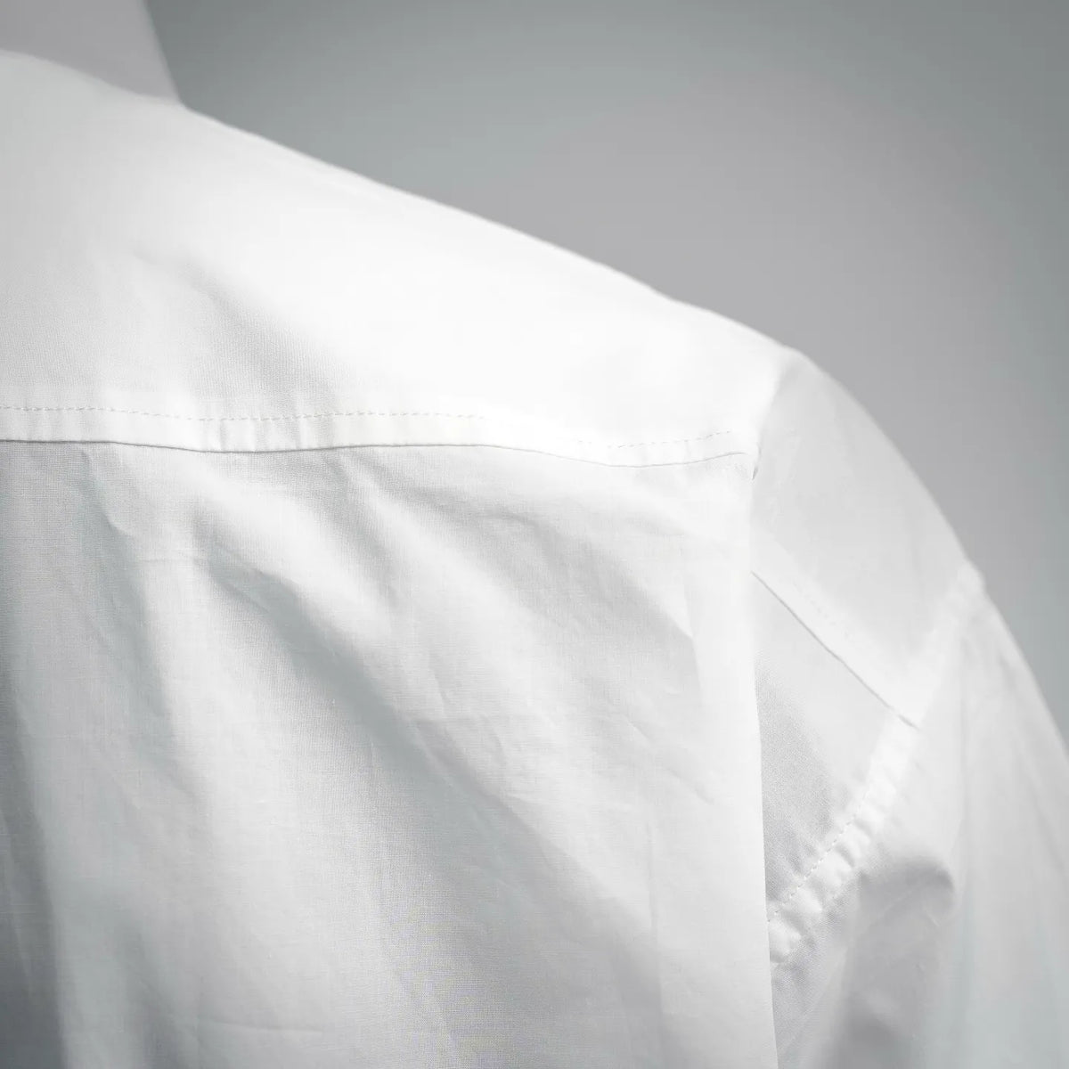 White short-sleeve shirt side panel with stitched seam close-up