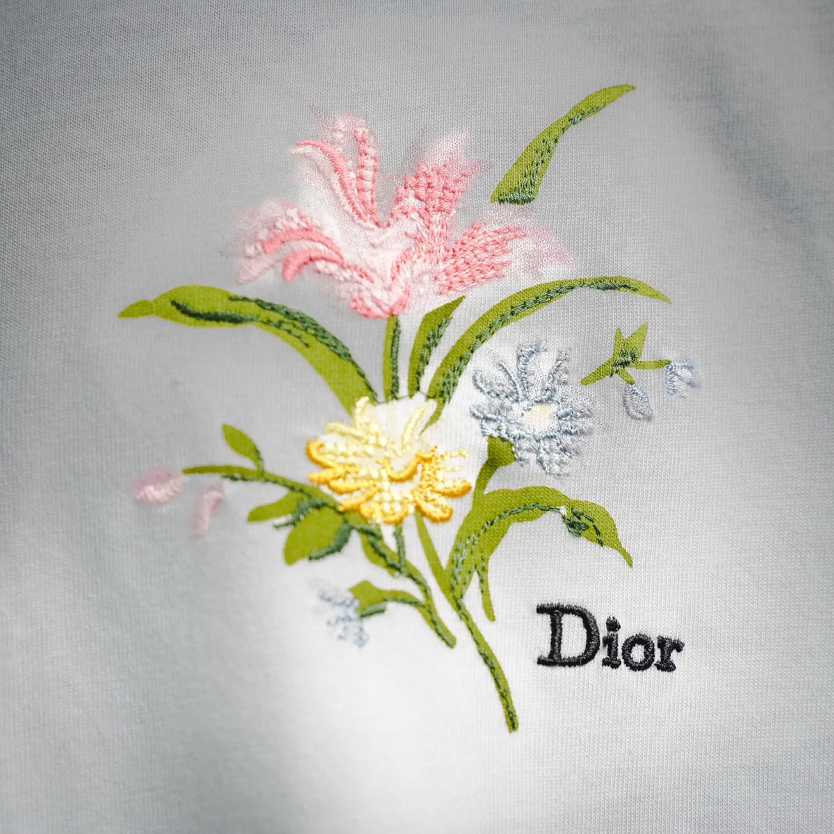 Close-up of colorful floral embroidery with Dior text on white T-shirt