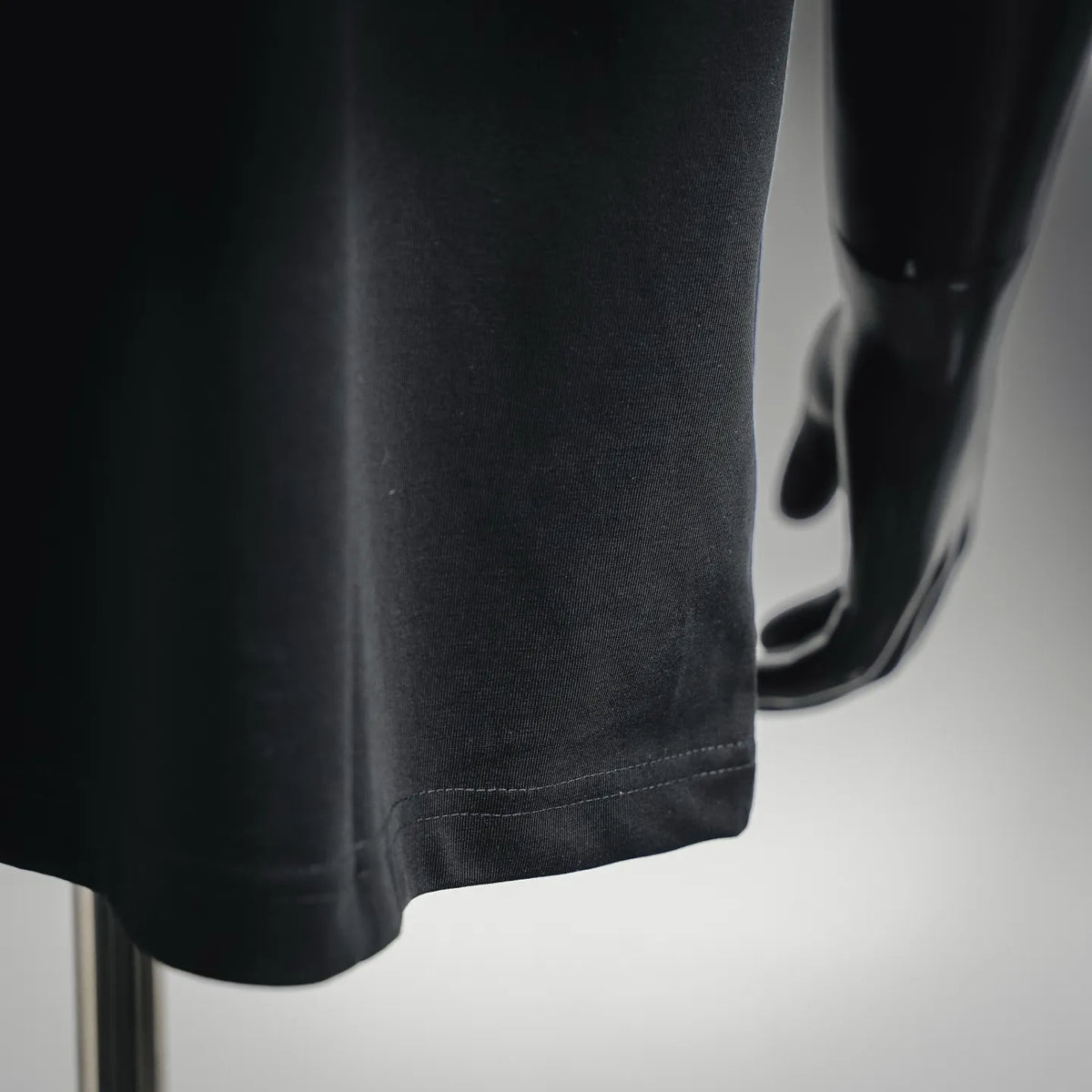Dior T-shirt lower hem and side seam stitching on dark fabric.