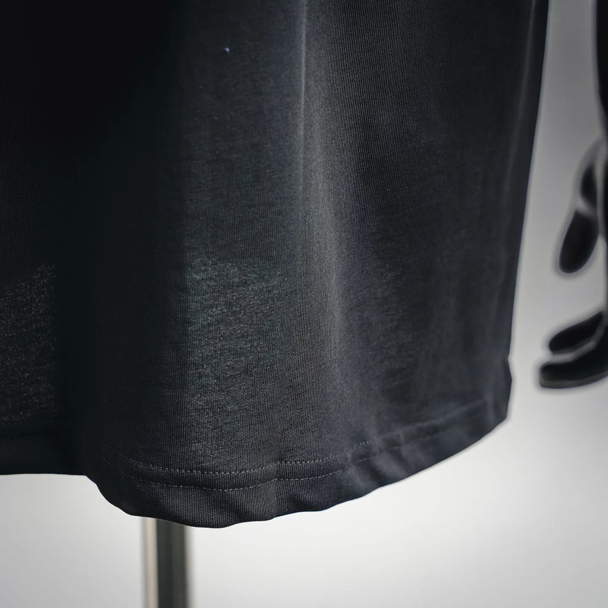 Black short-sleeve T-shirt hem close-up with visible stitching