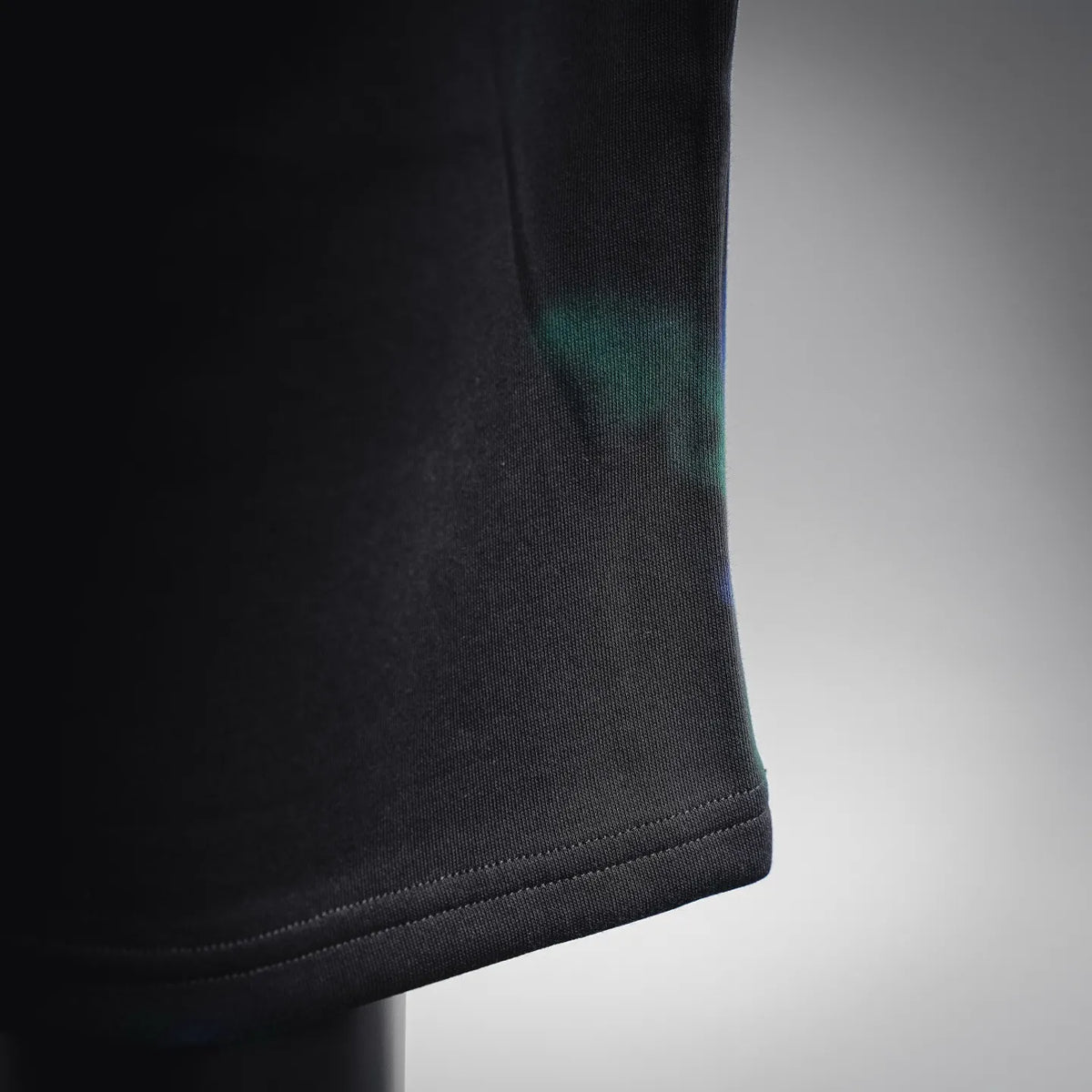 Black shorts leg hem with slight blue-green tint near the cuff