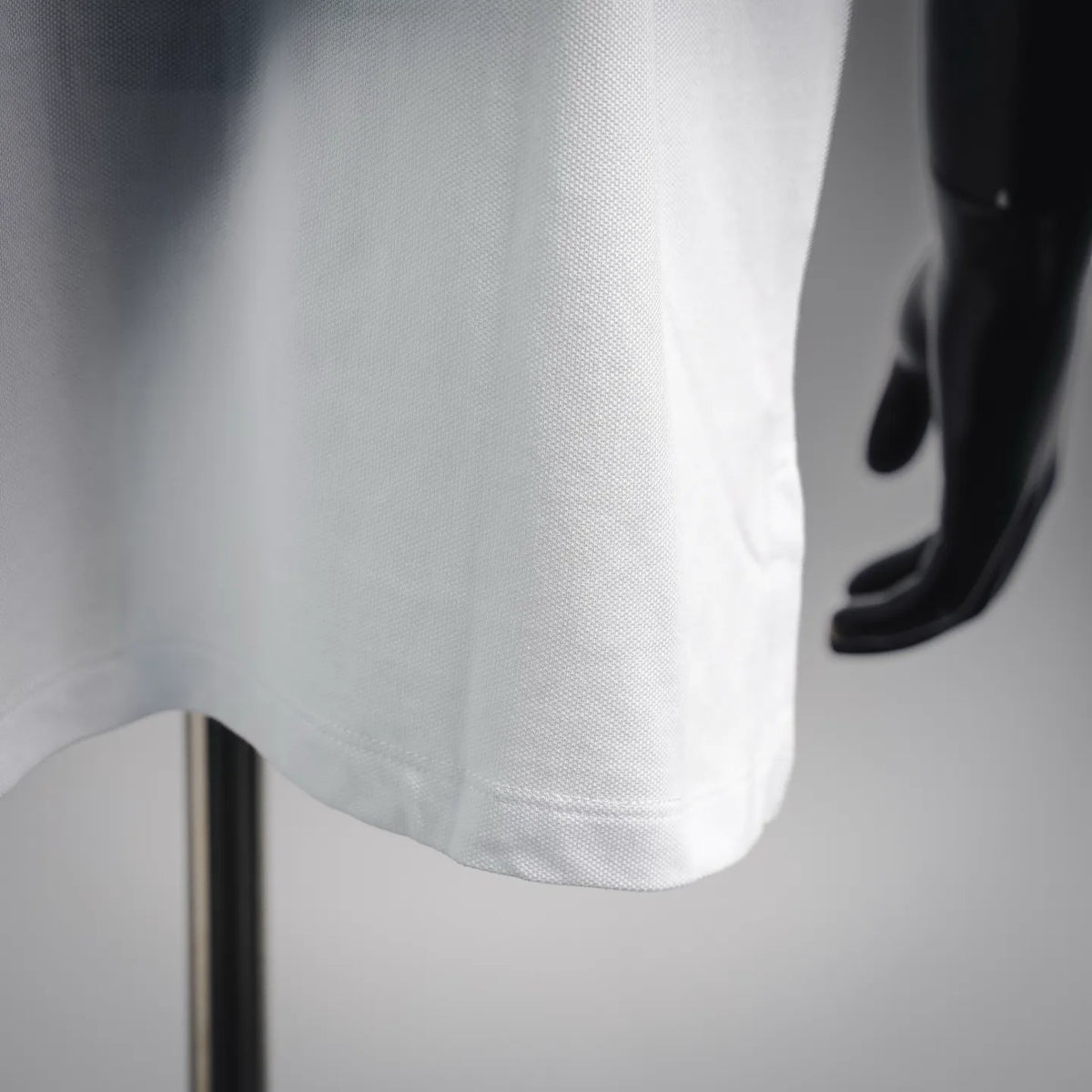 White polo shirt hem with subtle texture and curved side seam