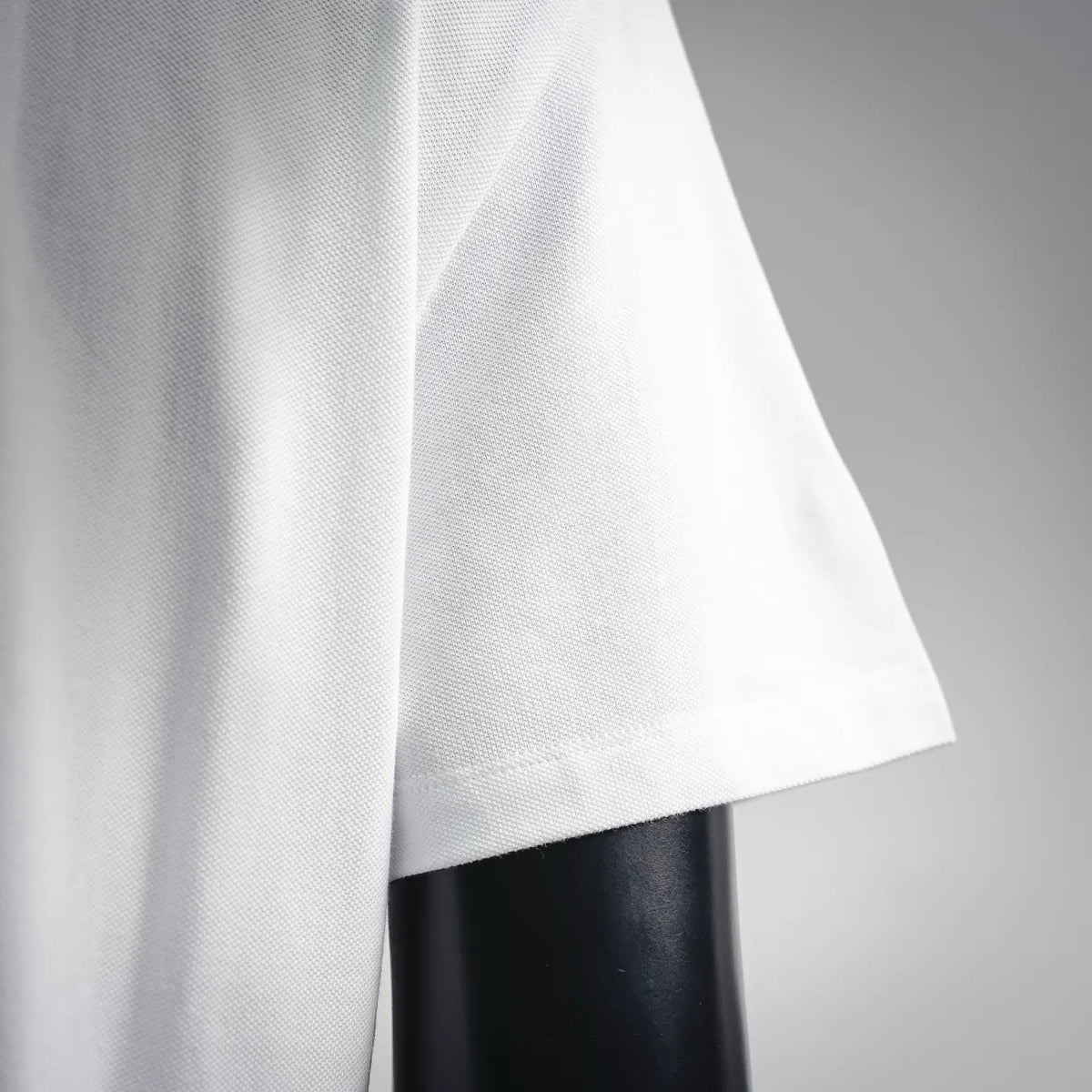 White polo shirt side panel with clean seam and short sleeve cuff