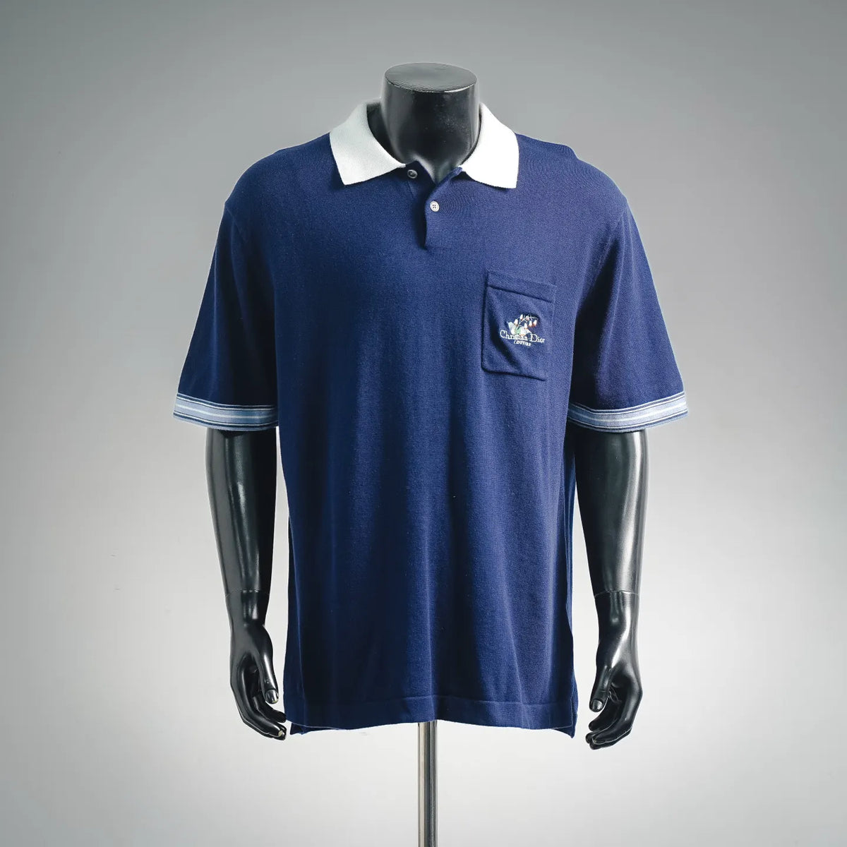 Navy Dior polo shirt with white collar, button placket, chest logo patch, striped sleeves