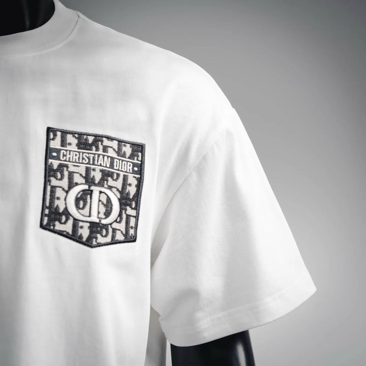 White short-sleeve T-shirt with black Dior logo patch near shoulder