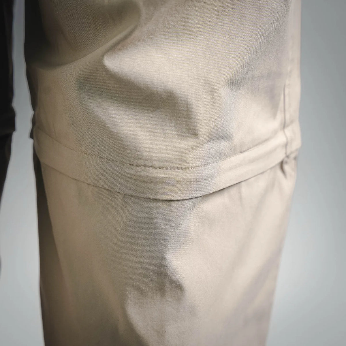 Close-up of tan pants fabric with curved yoke seam at the hip