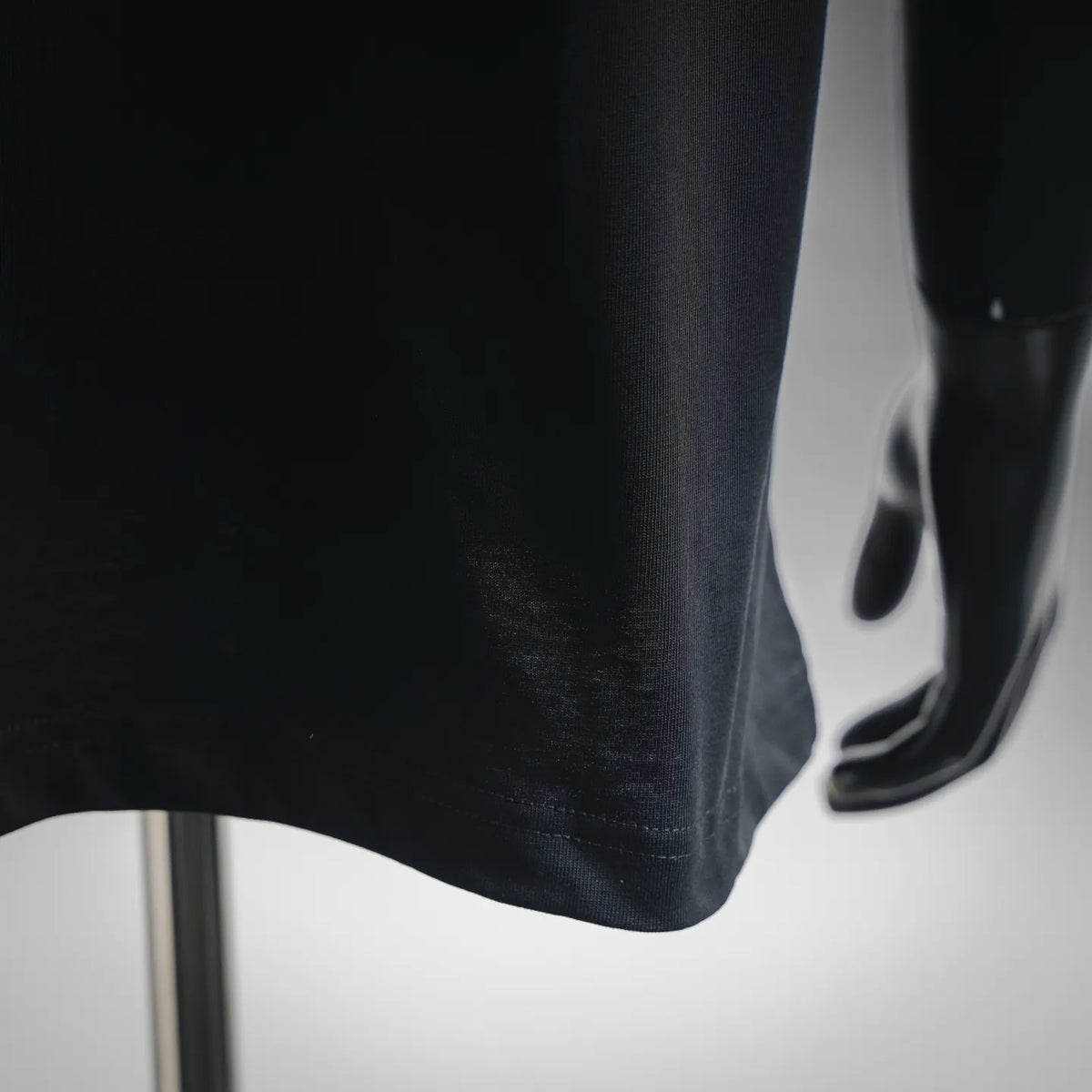 Black T-shirt fabric close-up at sleeve hem with visible stitching