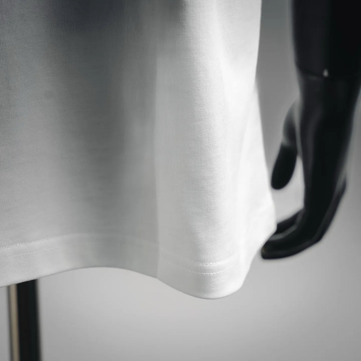 White T-shirt hem and sleeve seam detail with smooth fabric texture.