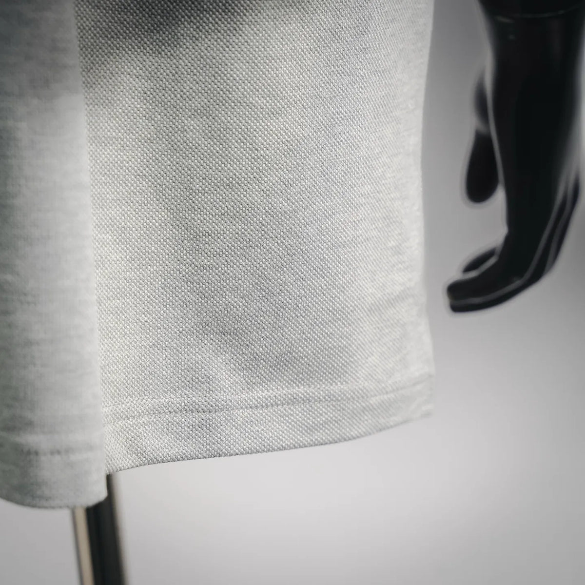 Light gray polo shirt sleeve cuff with subtle knit texture and stitched hem
