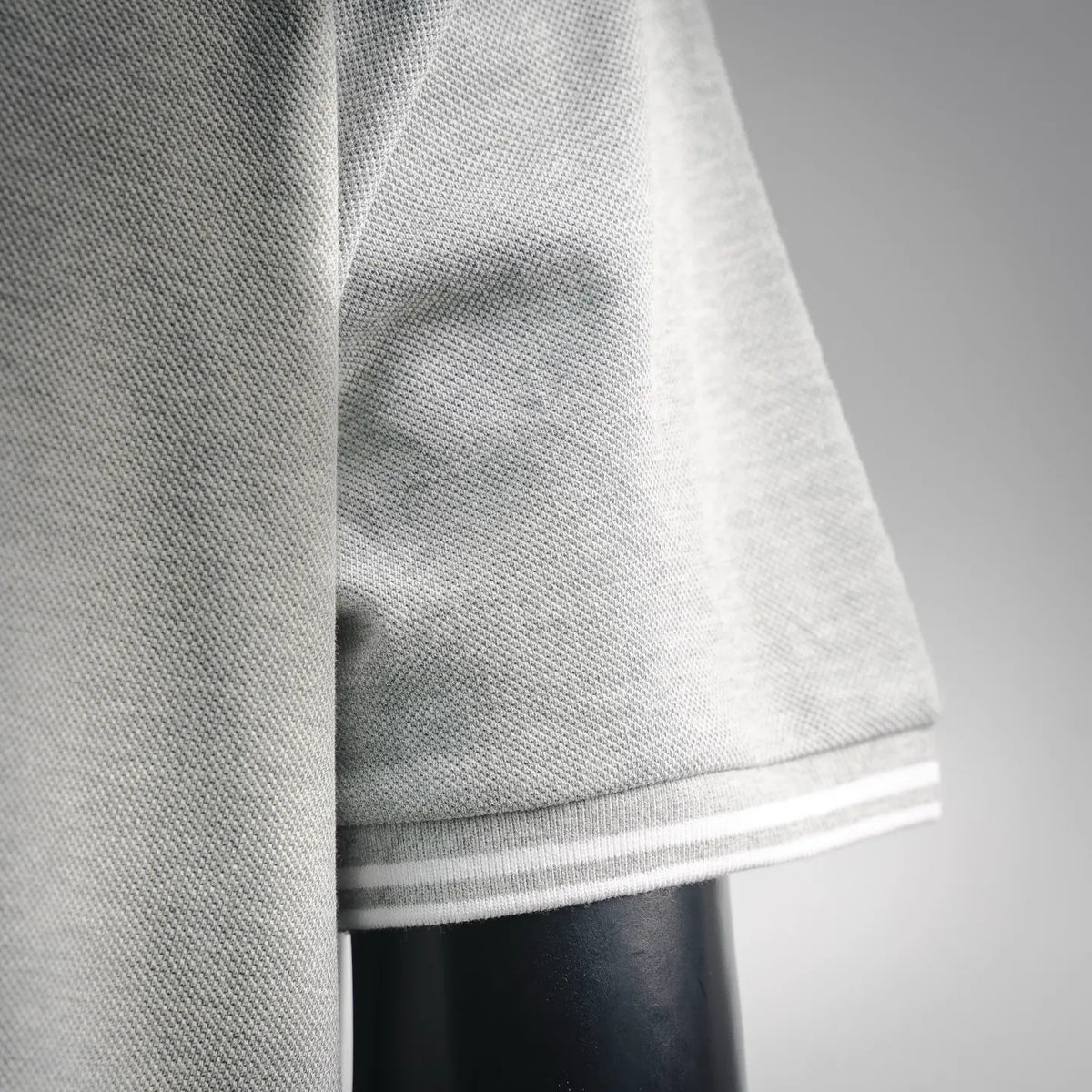 Light gray polo shirt hem with white striped trim at sleeve end