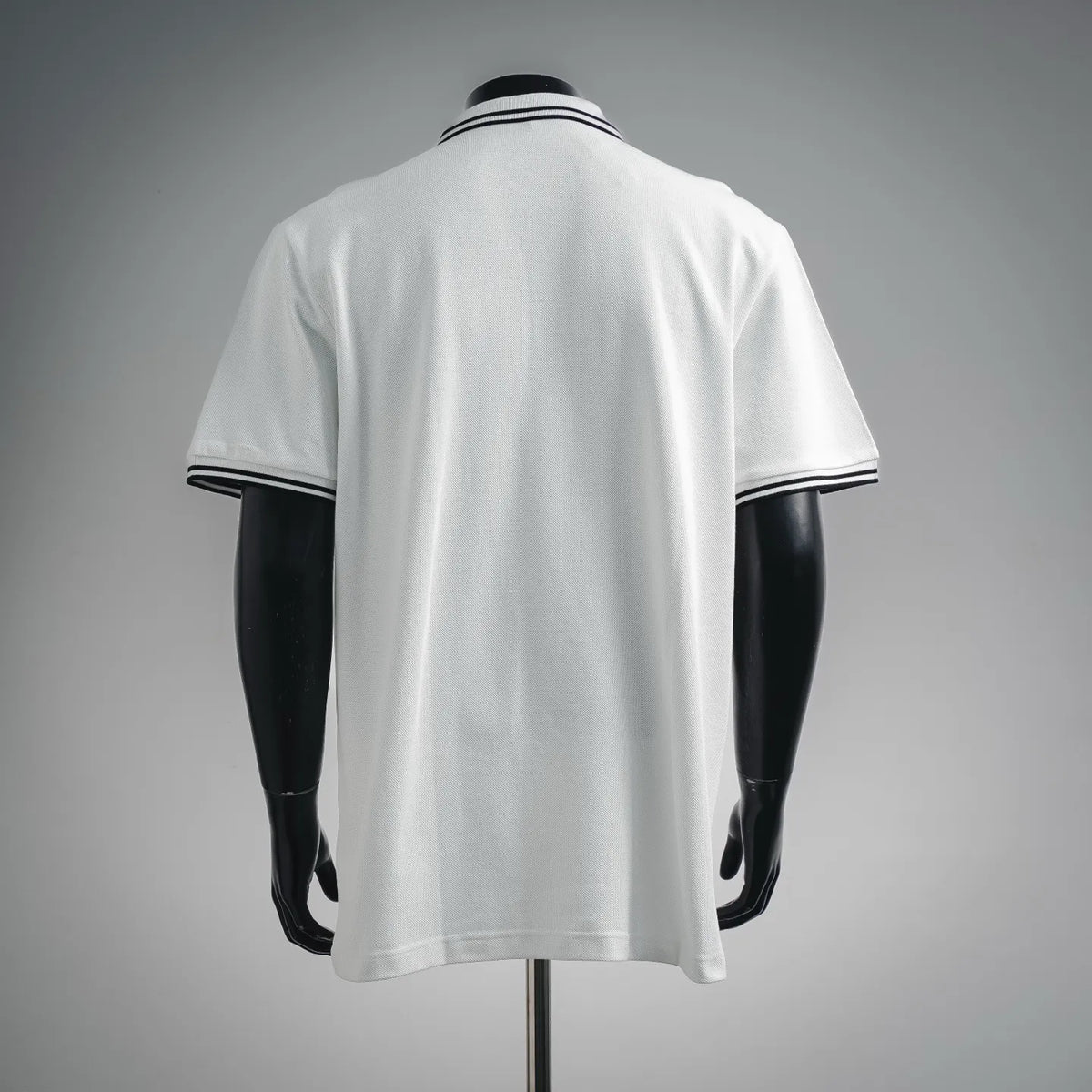 White polo shirt back view with navy-striped collar and sleeve cuffs