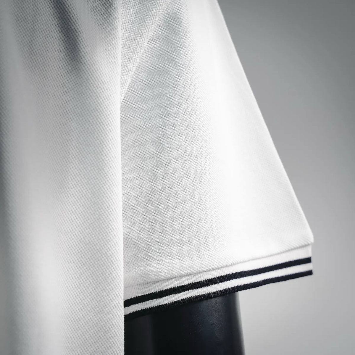 White polo sleeve hem with navy-and-white ribbed stripe trim