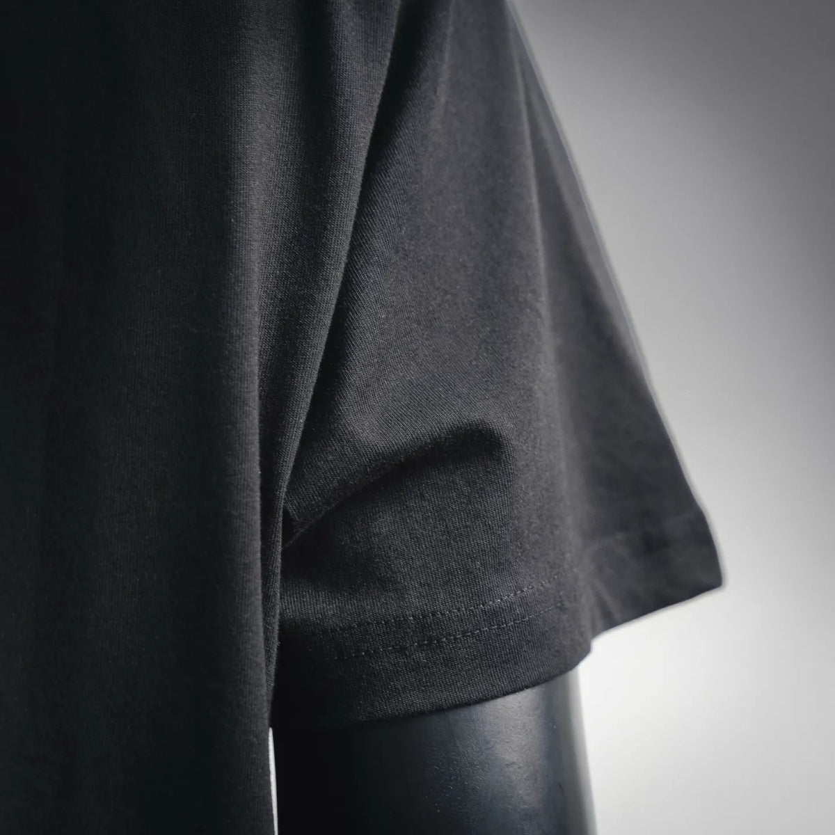 Black Dior T-shirt sleeve and hem close-up, showing fabric texture