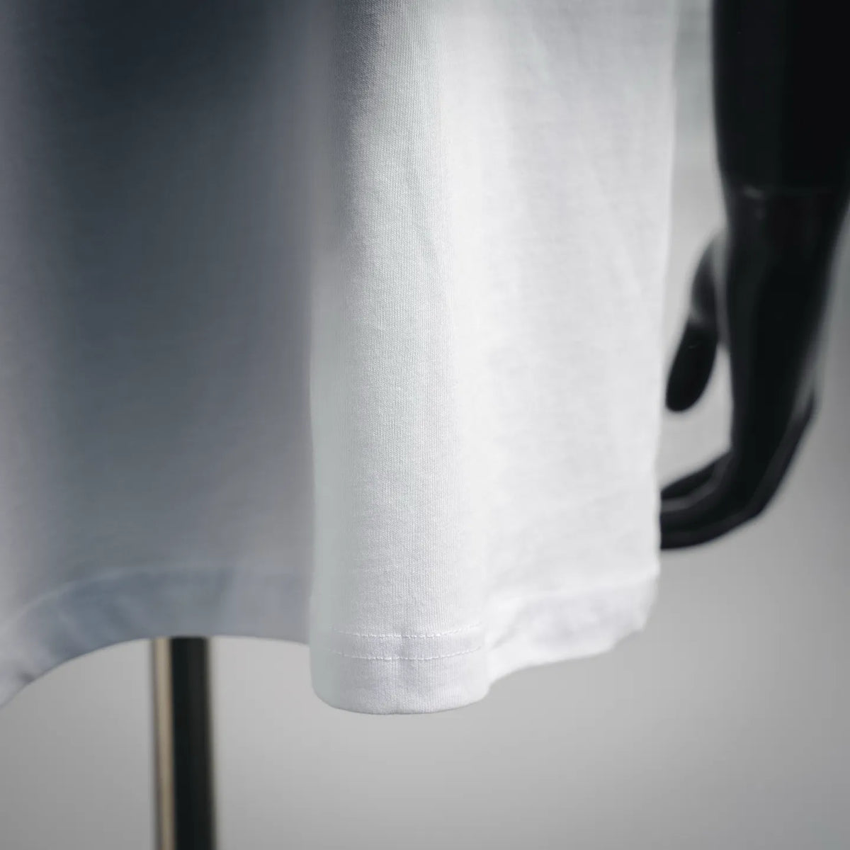 White Dior T-shirt hem and side drape, close-up on lower front.