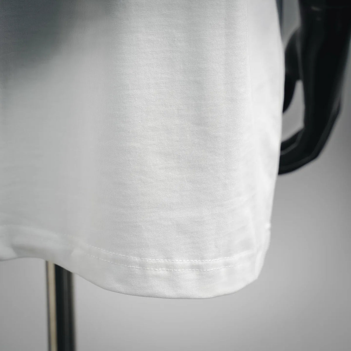 Dior white T-shirt fabric close-up with curved hem and stitching