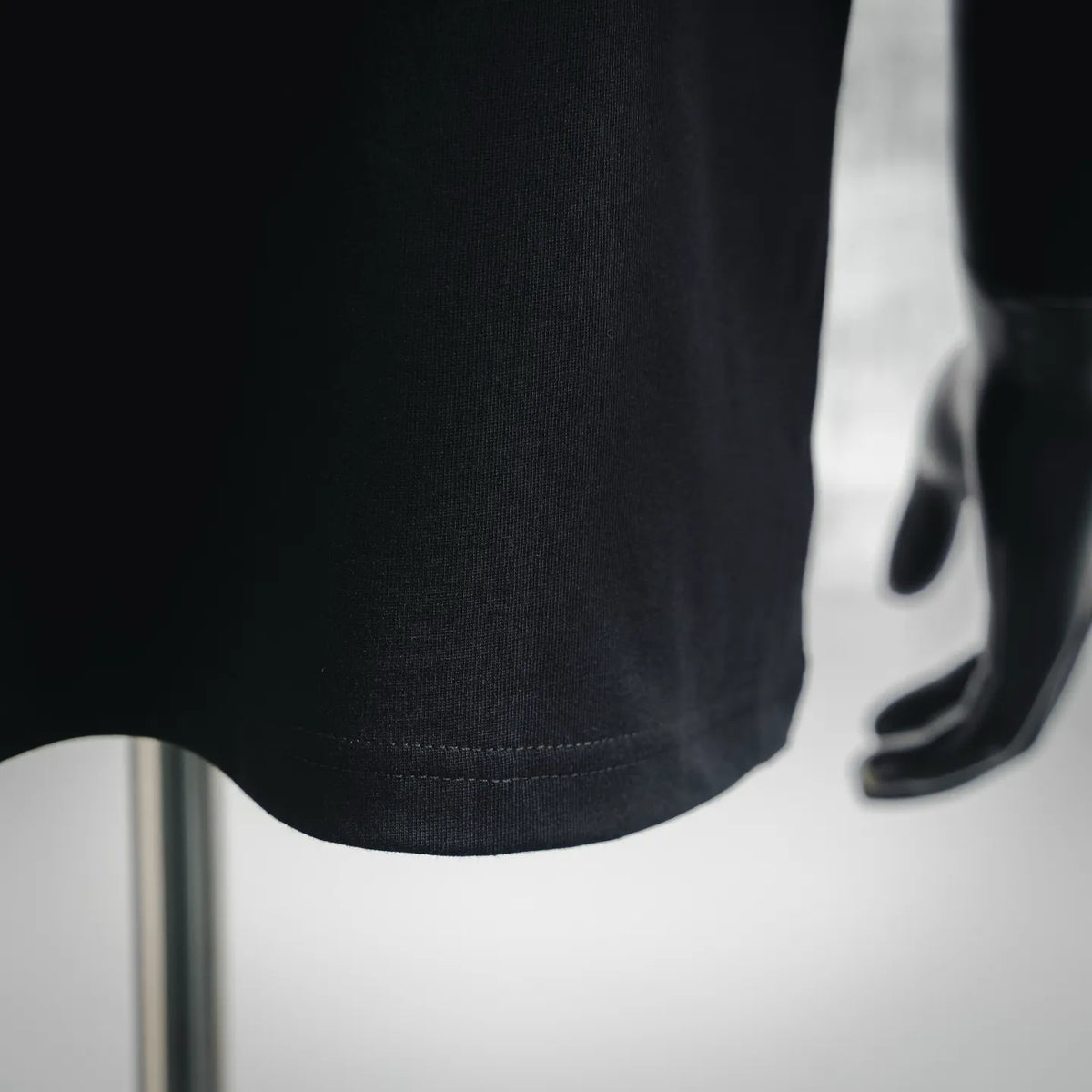 Black T-shirt hem with straight stitched edge at bottom