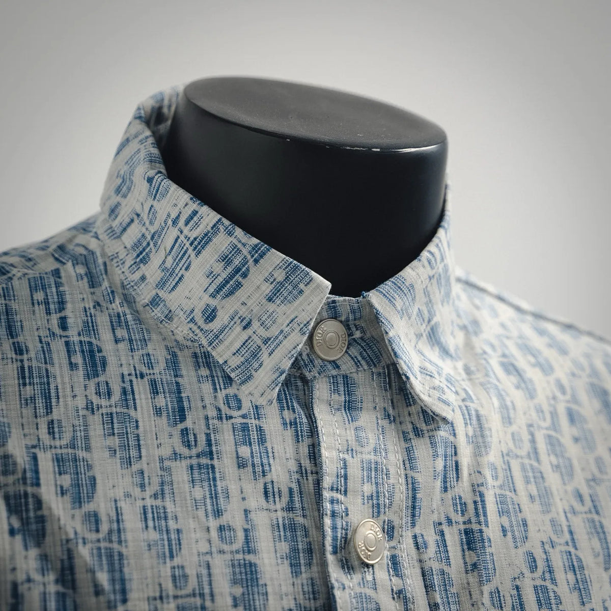 Light blue patterned long-sleeve shirt with metal buttons at the neckline.