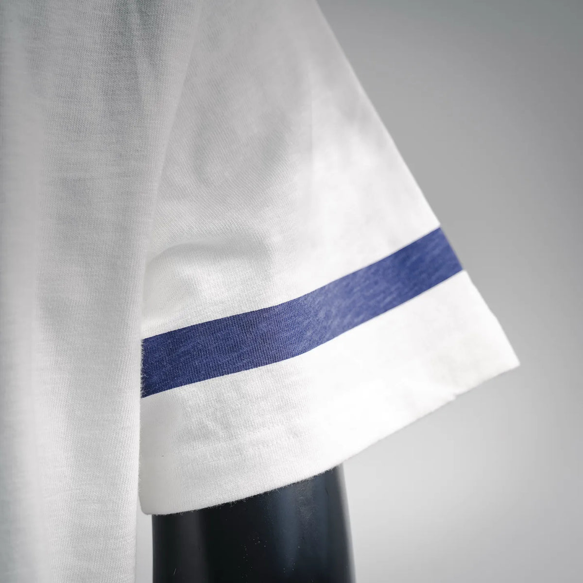 White short-sleeve T-shirt with a blue stripe band at the sleeve hem.