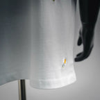 White T-shirt fabric close-up with small daisy embroidery near hem