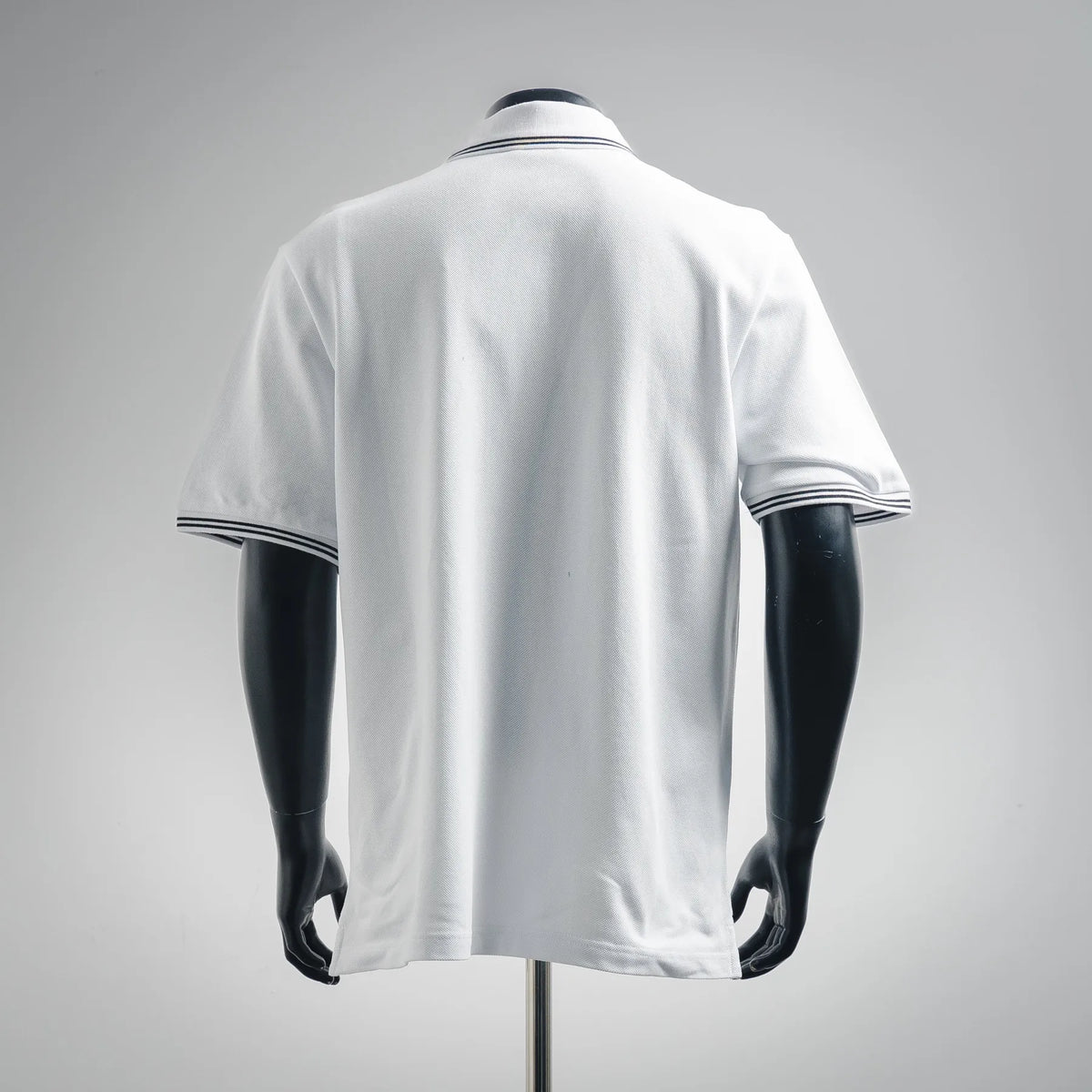 White short-sleeve polo shirt with navy striped collar and sleeve cuffs, shown from the back