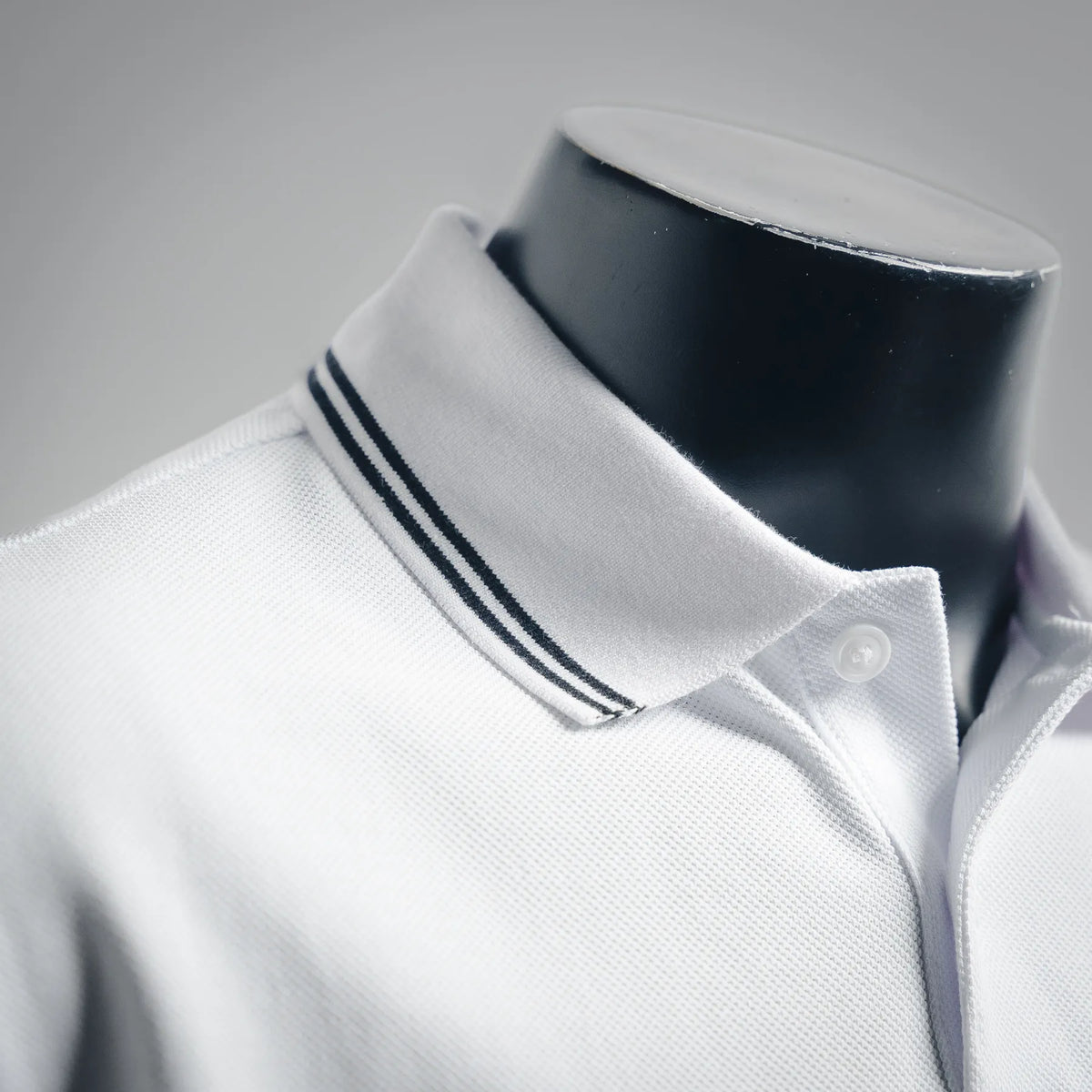 White polo collar with navy stripe trim and buttoned placket, close-up on neckline