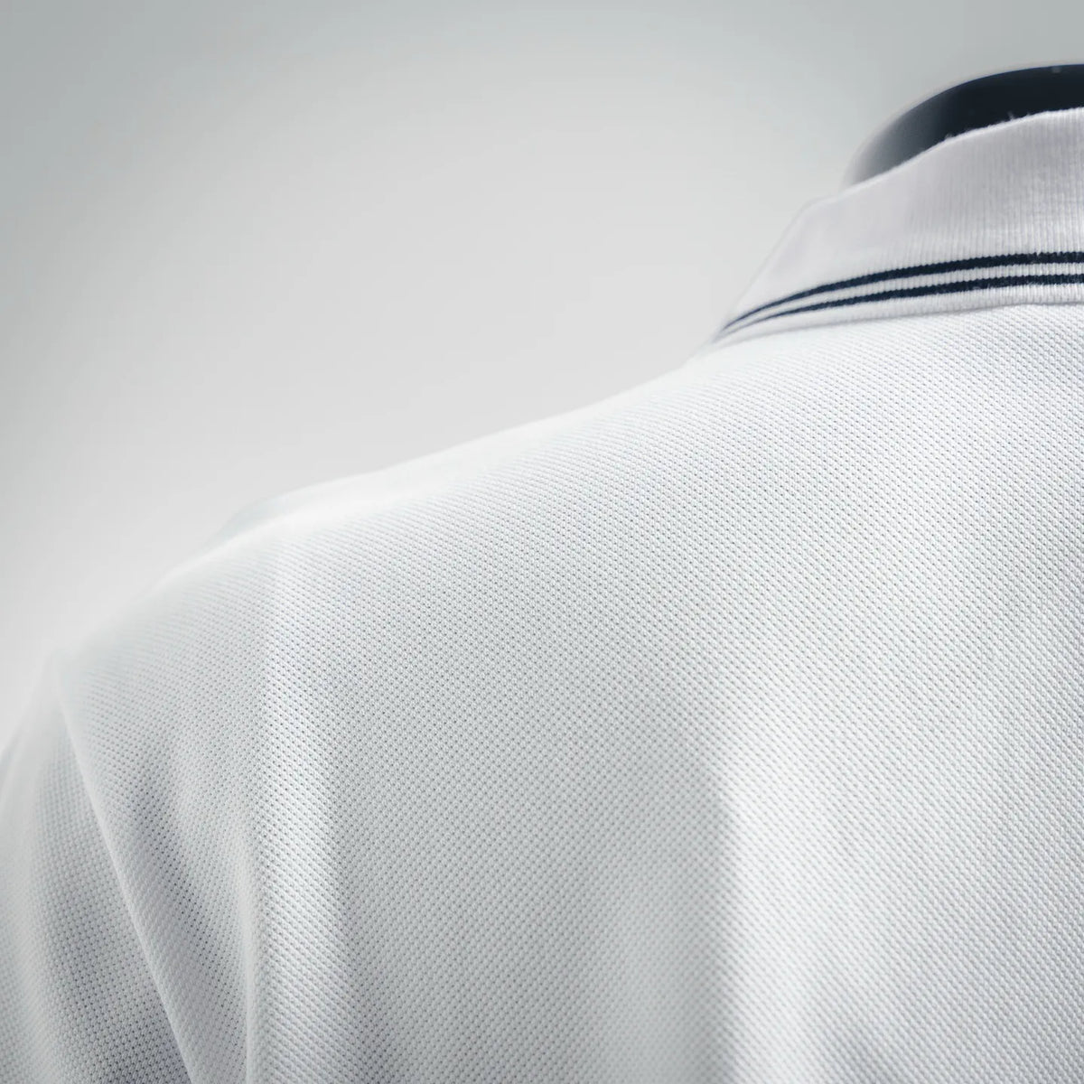 White polo shirt fabric close-up on the back with navy-striped sleeve cuff trim