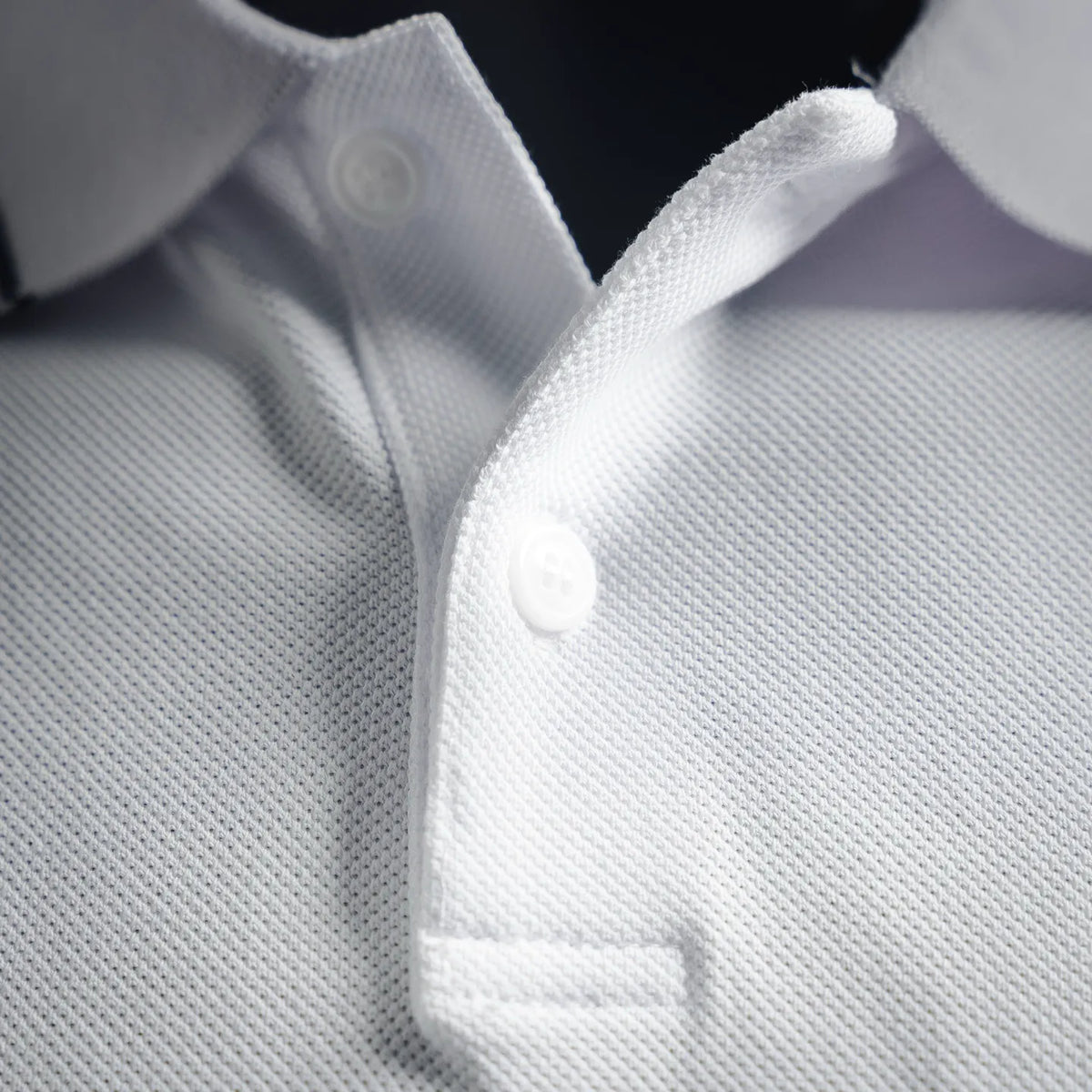 White polo placket with two buttons and ribbed collar, close-up view