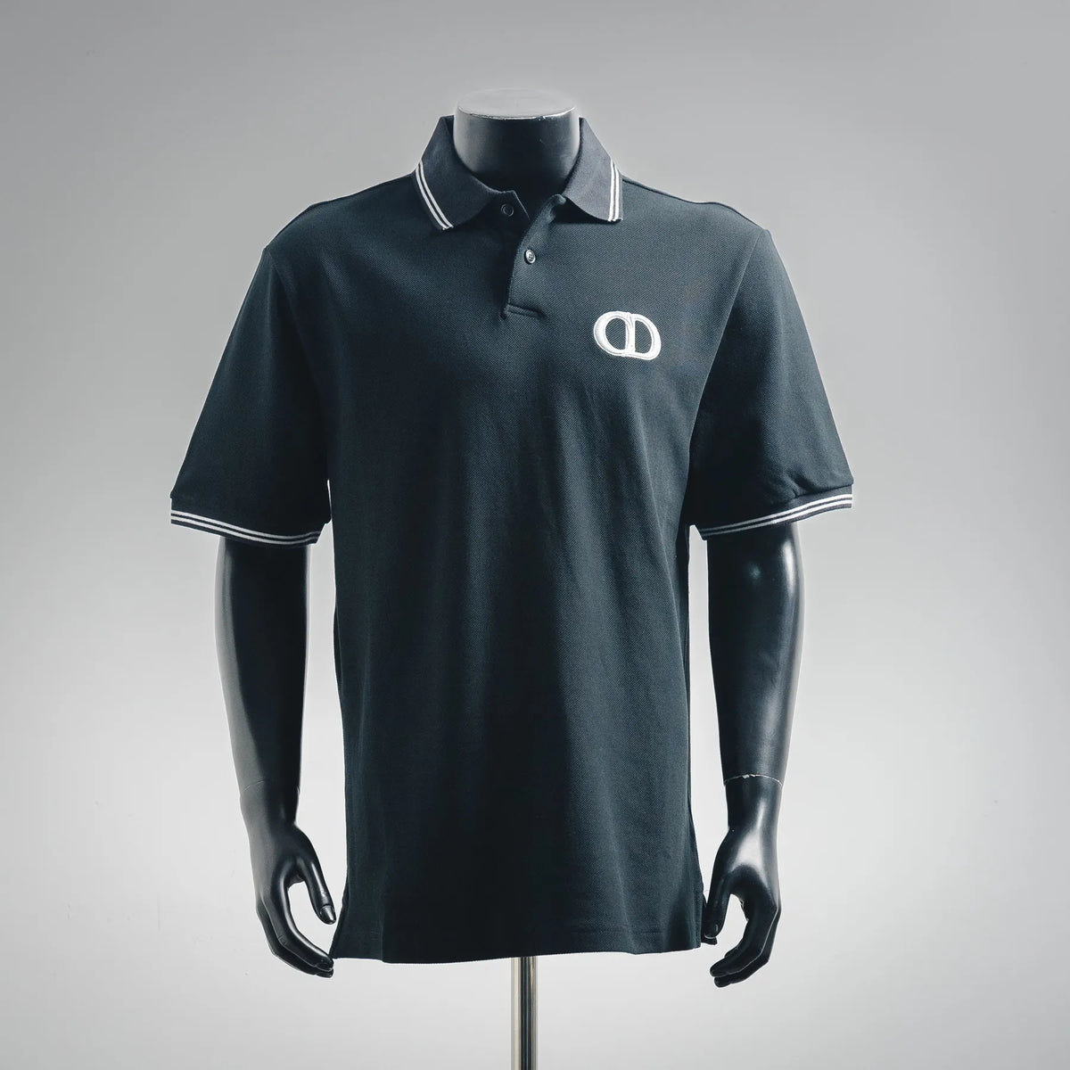 Navy short-sleeve polo shirt with striped collar and embroidered CD logo at chest