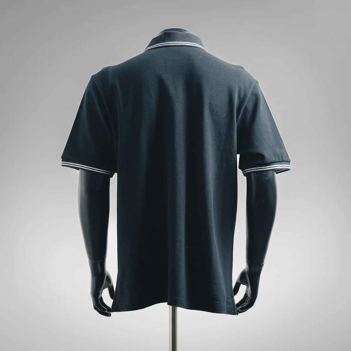 Back view of navy short-sleeve polo shirt with striped collar trim