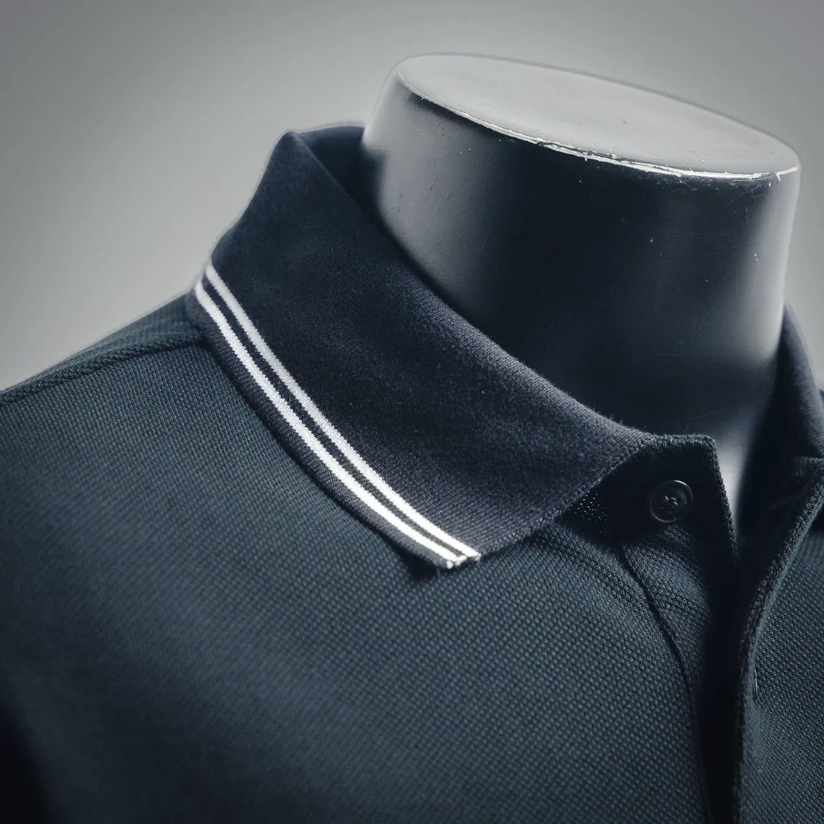 Navy polo collar with white-and-gray striped trim and snap-button placket