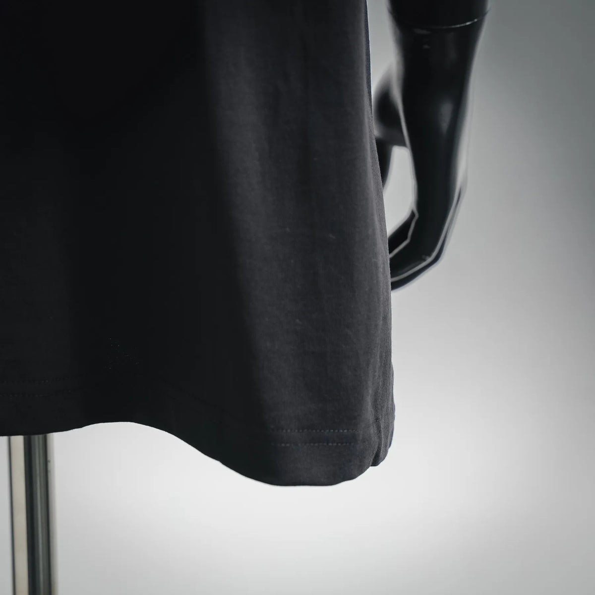 Black Dior T-shirt hem close-up, straight hem stitching and fabric drape