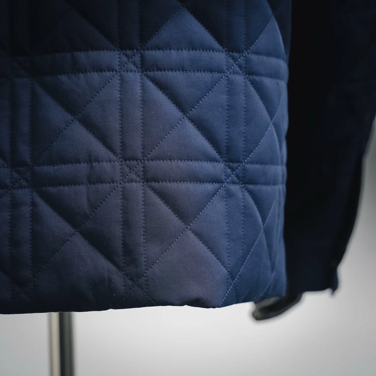 Close-up of dark navy quilted fabric with diamond stitching