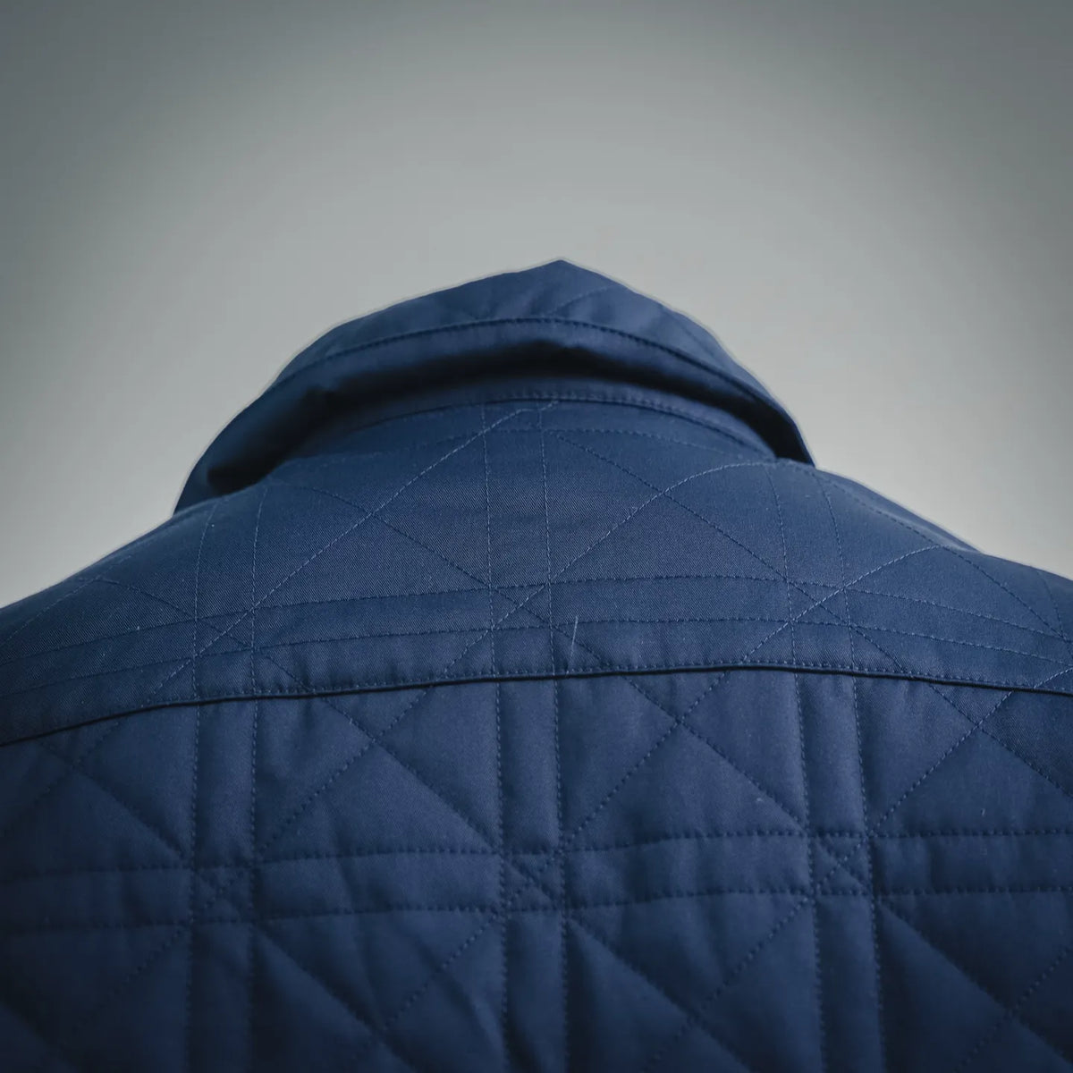 Blue quilted coat with raised collar and stitched shoulder yoke