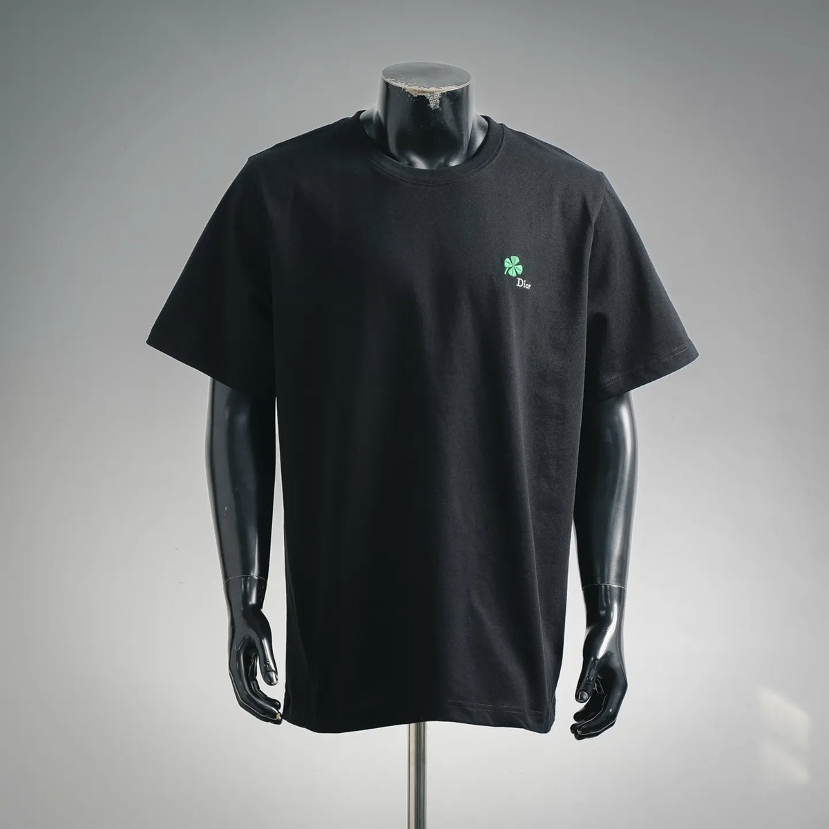 Black short-sleeve T-shirt with green Dior clover logo on chest