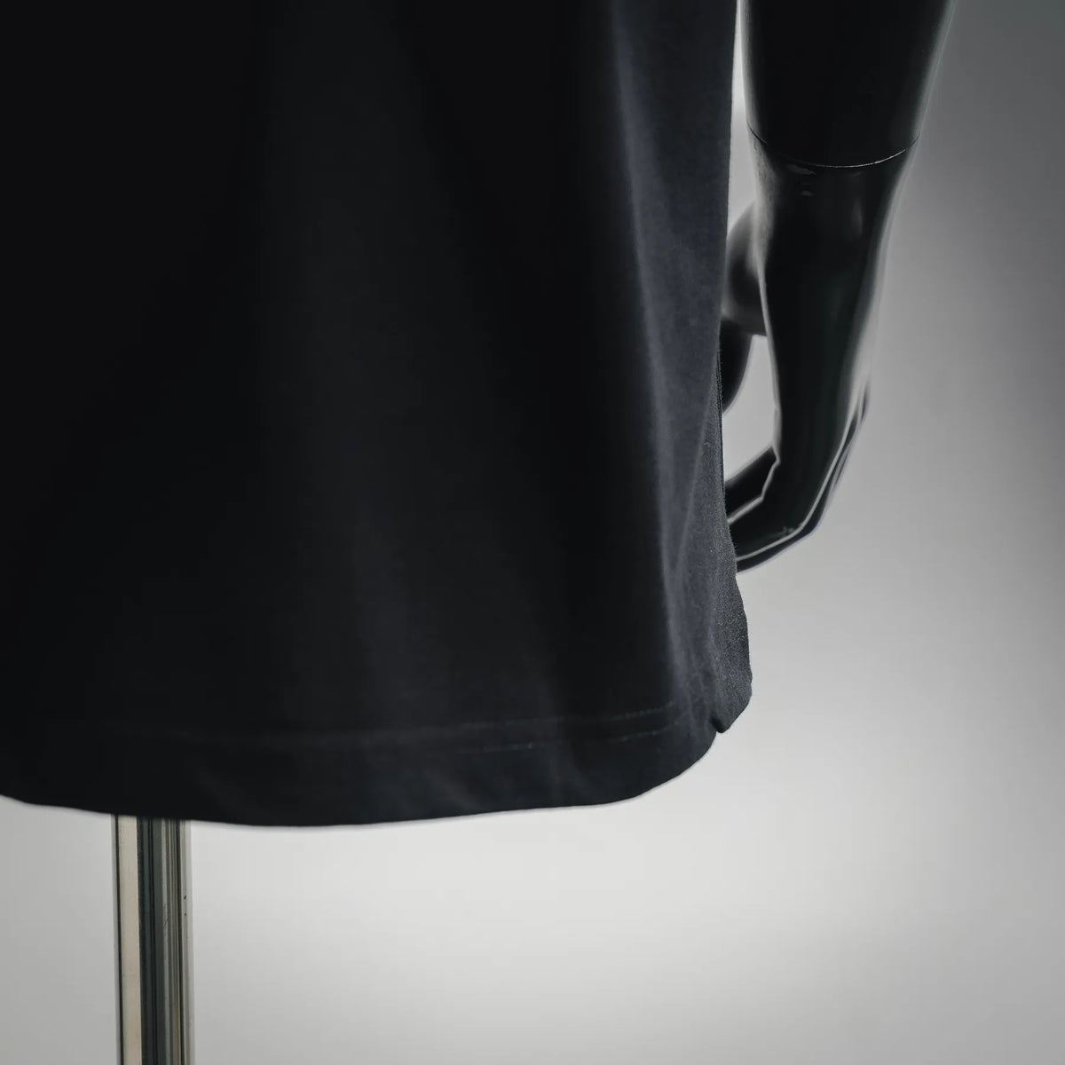 Black T-shirt side view showing curved hem and short sleeve seam