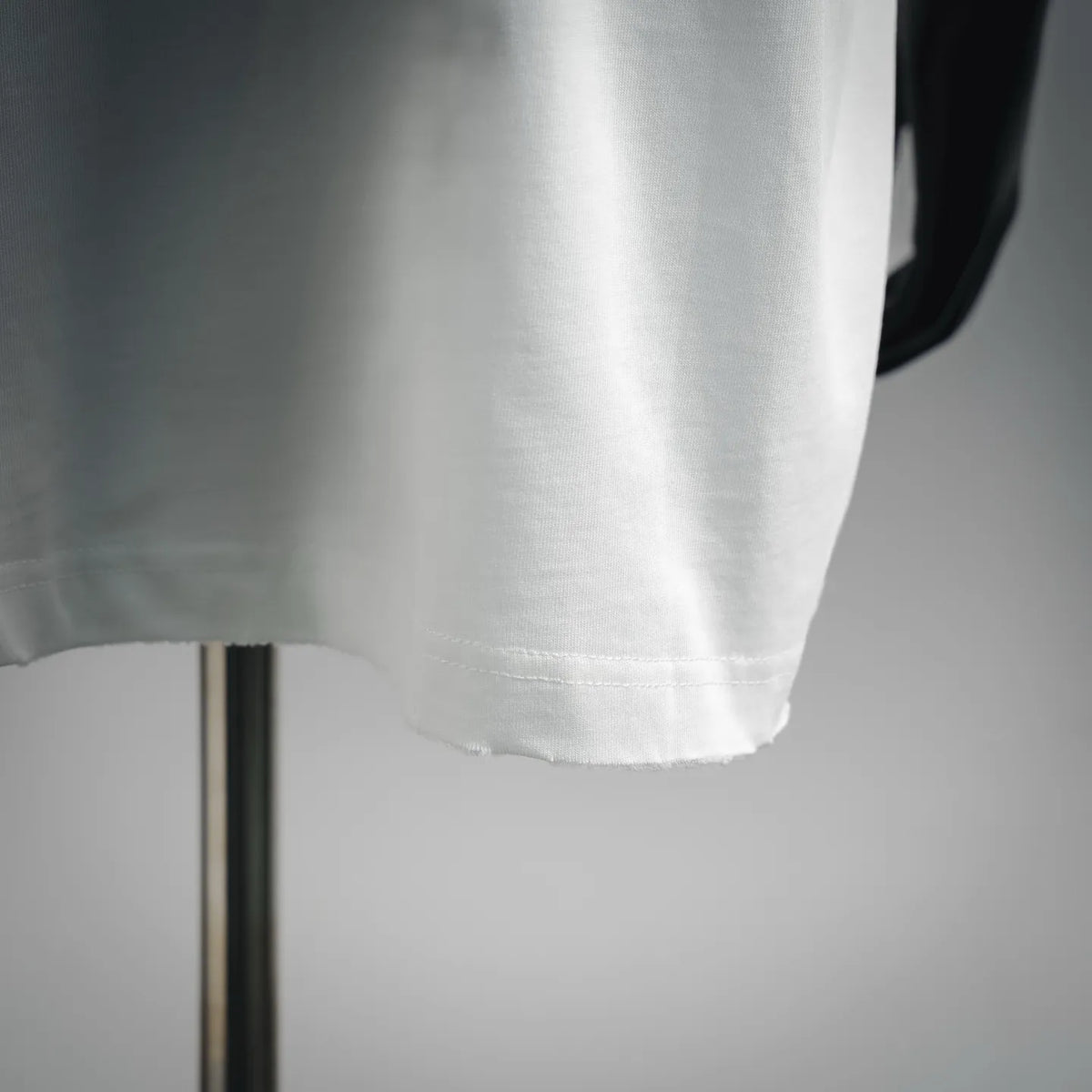 Dior white t-shirt hem close-up with stitched edge and fabric texture