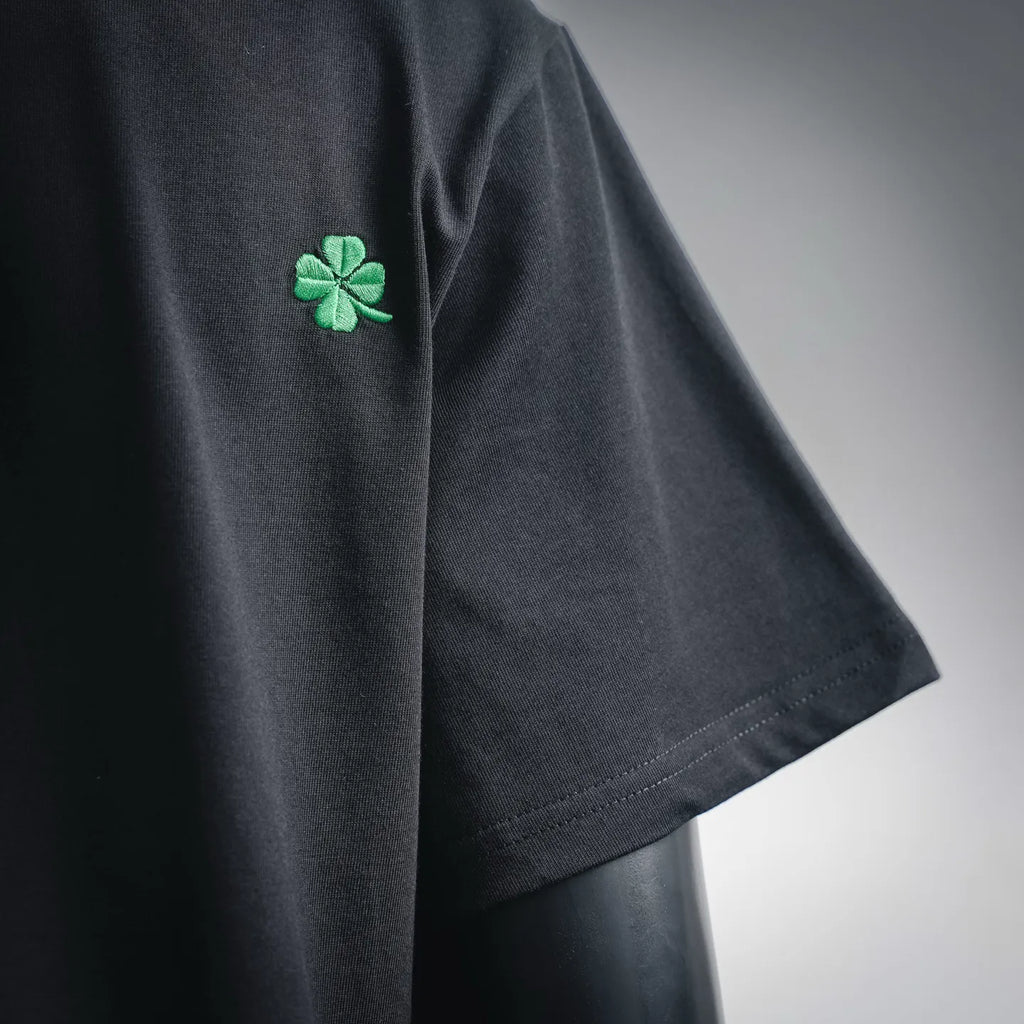 Black T-shirt sleeve with green clover logo