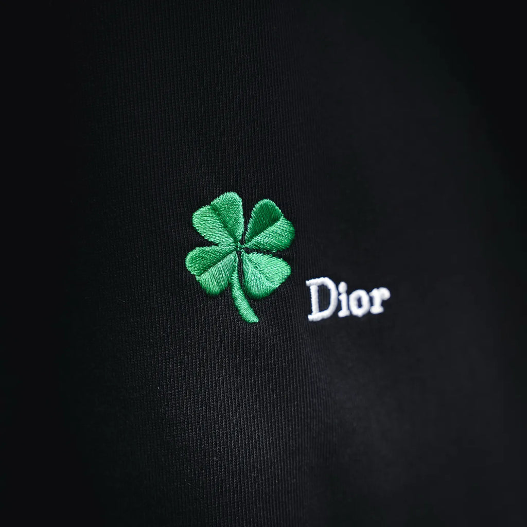 Black fabric closeup with green clover and Dior embroidery