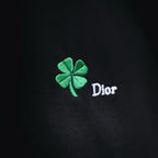 Black fabric closeup with green clover and Dior embroidery