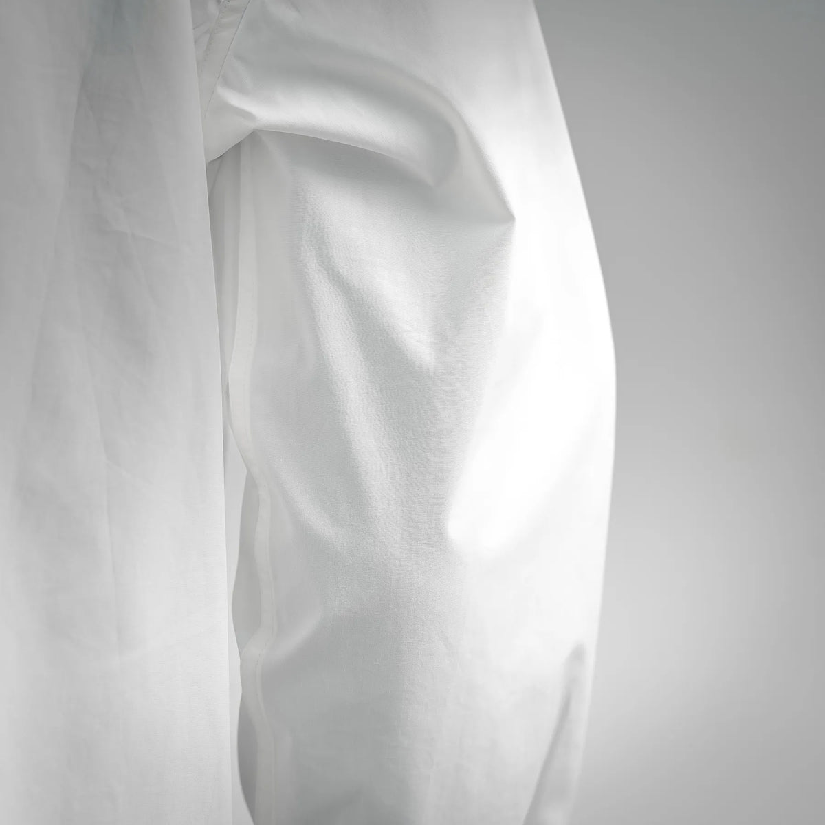 White cotton shirt fabric close-up showing smooth texture and drape