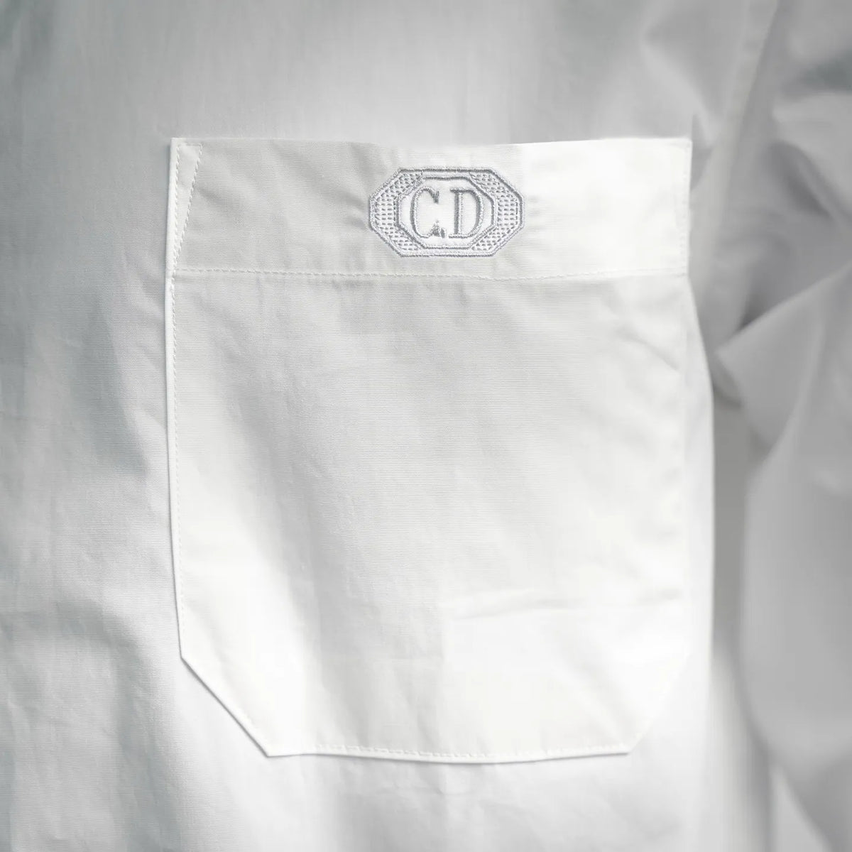 White shirt chest pocket close-up with CD monogram patch