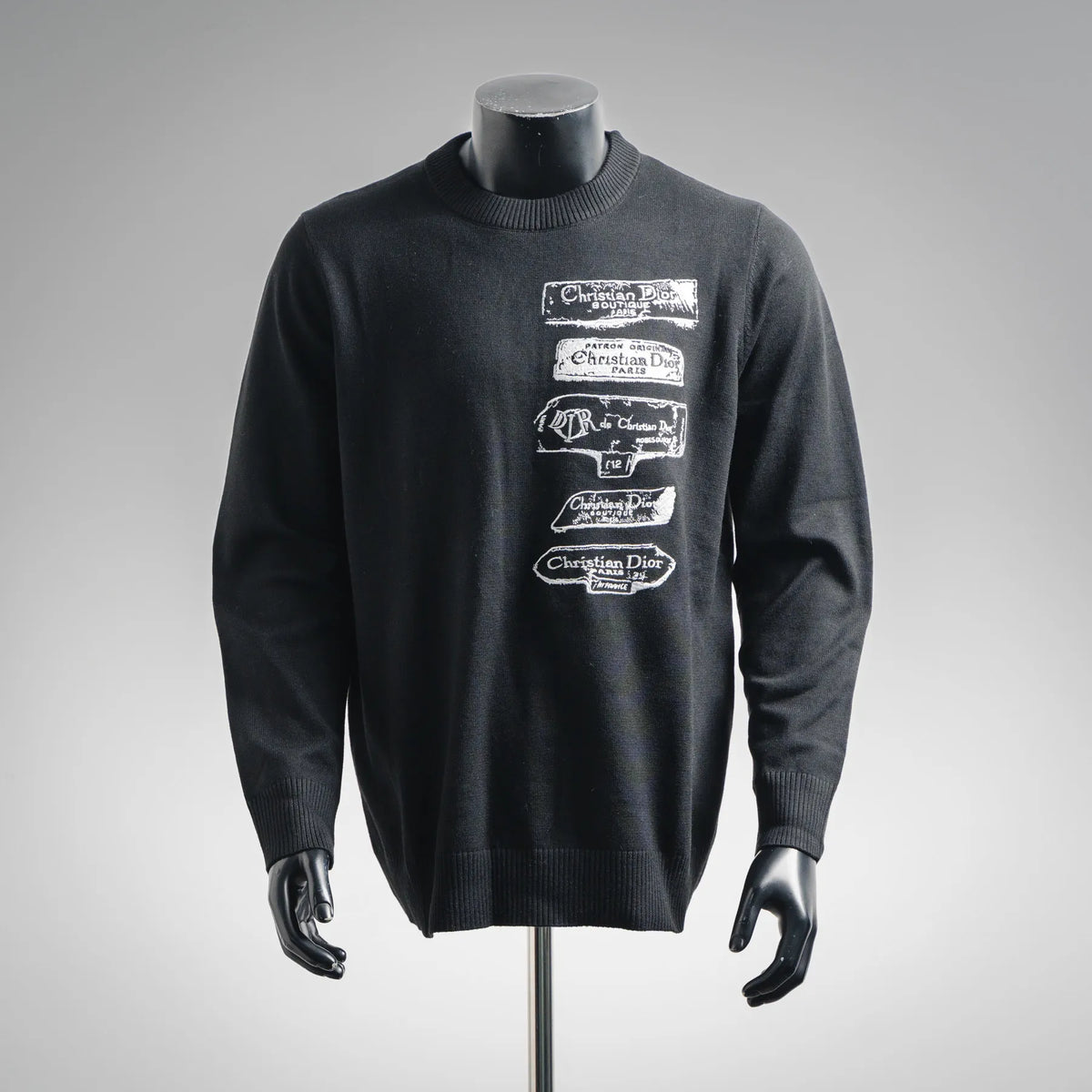 Black crewneck knit sweater with long sleeves and embroidered label graphic