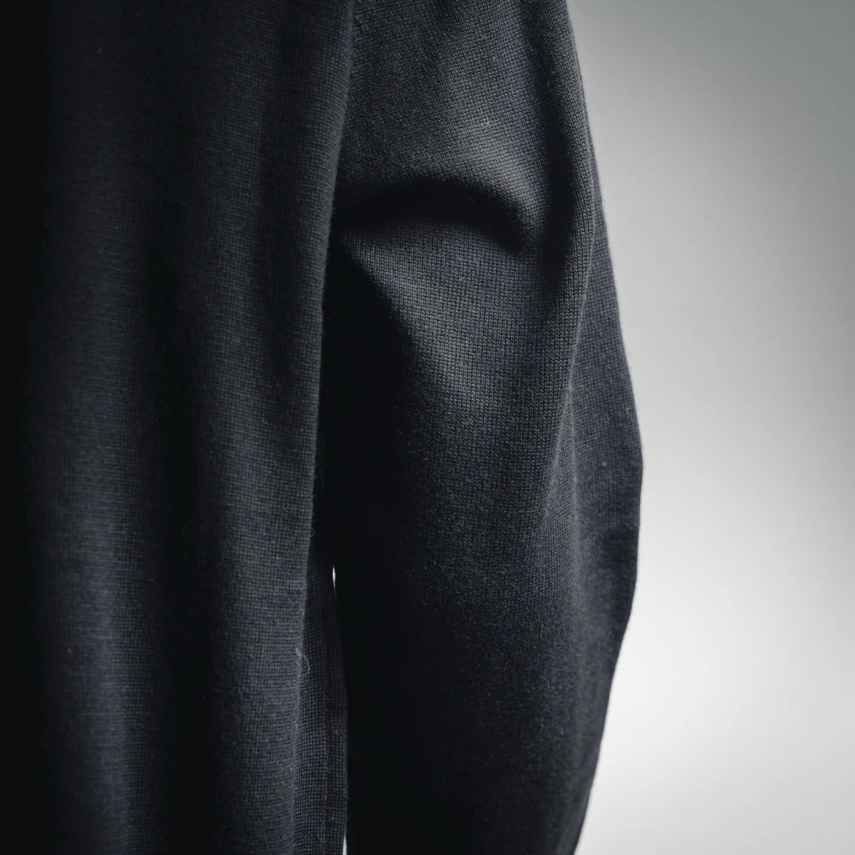 Black knit sweater sleeve fabric with subtle texture and soft drape